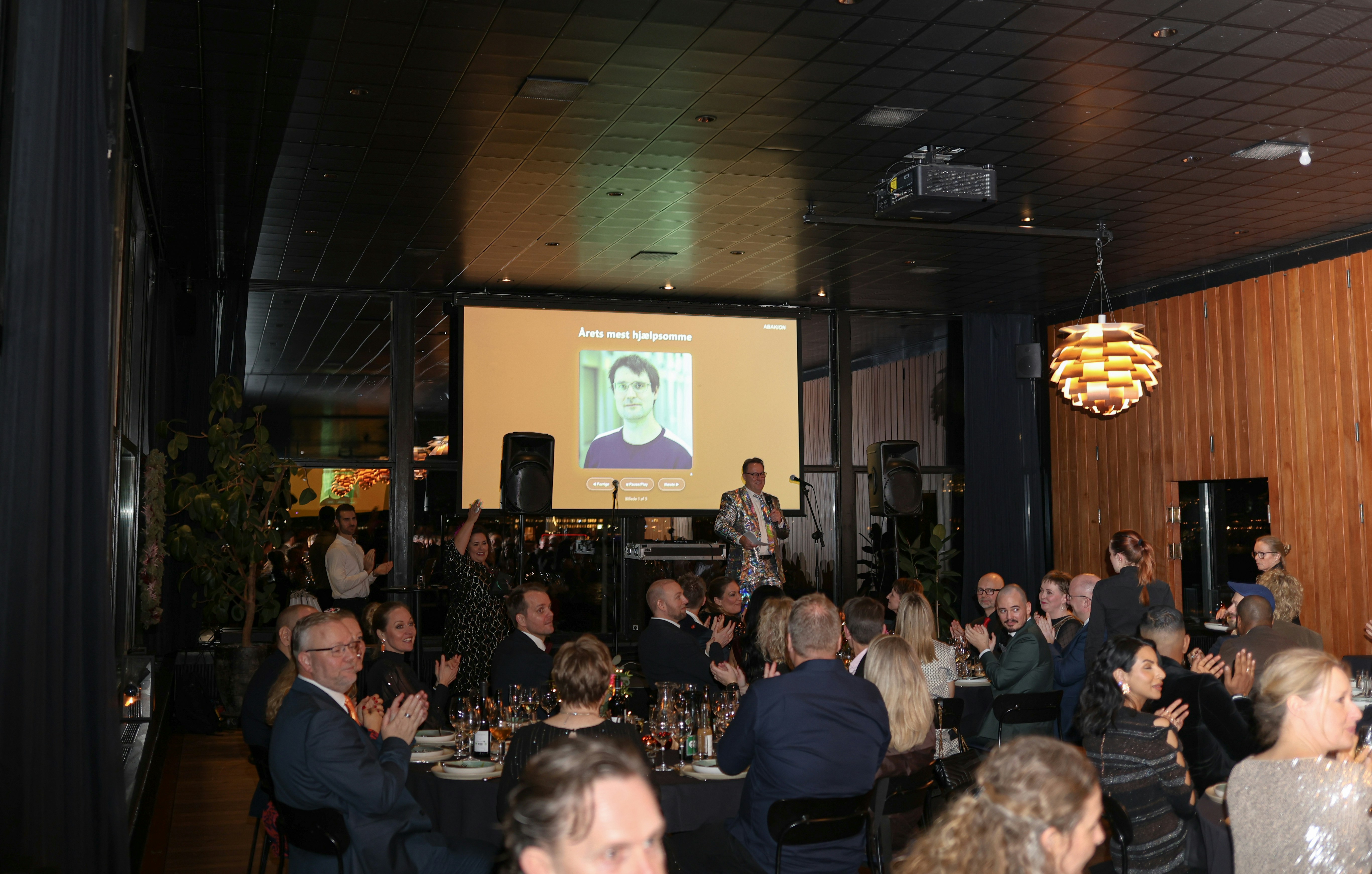 People gathered at an event with a presentation on screen.