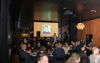 People gathered at an event with a presentation on screen.