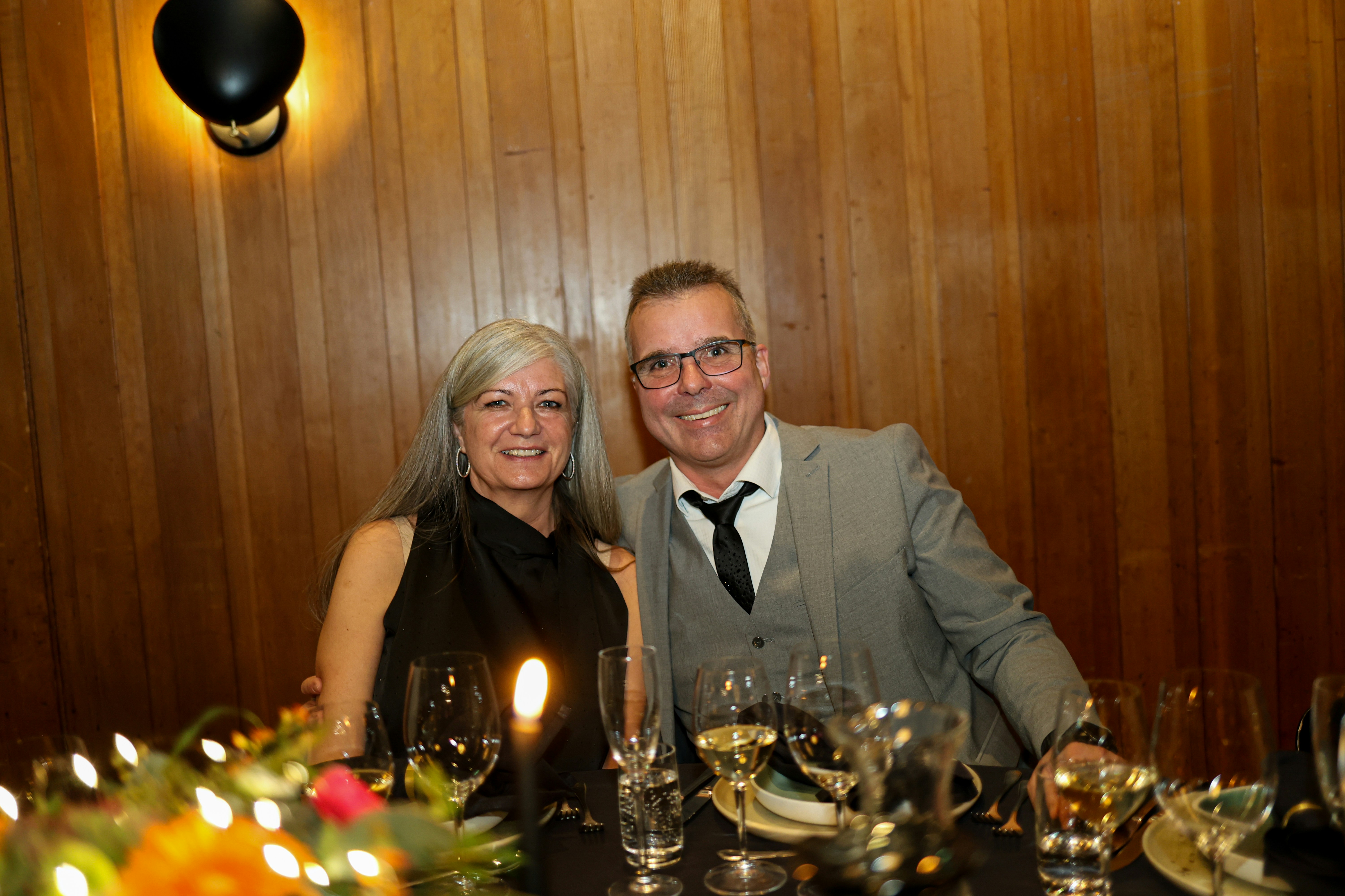 A couple smiles at a formal dinner party.