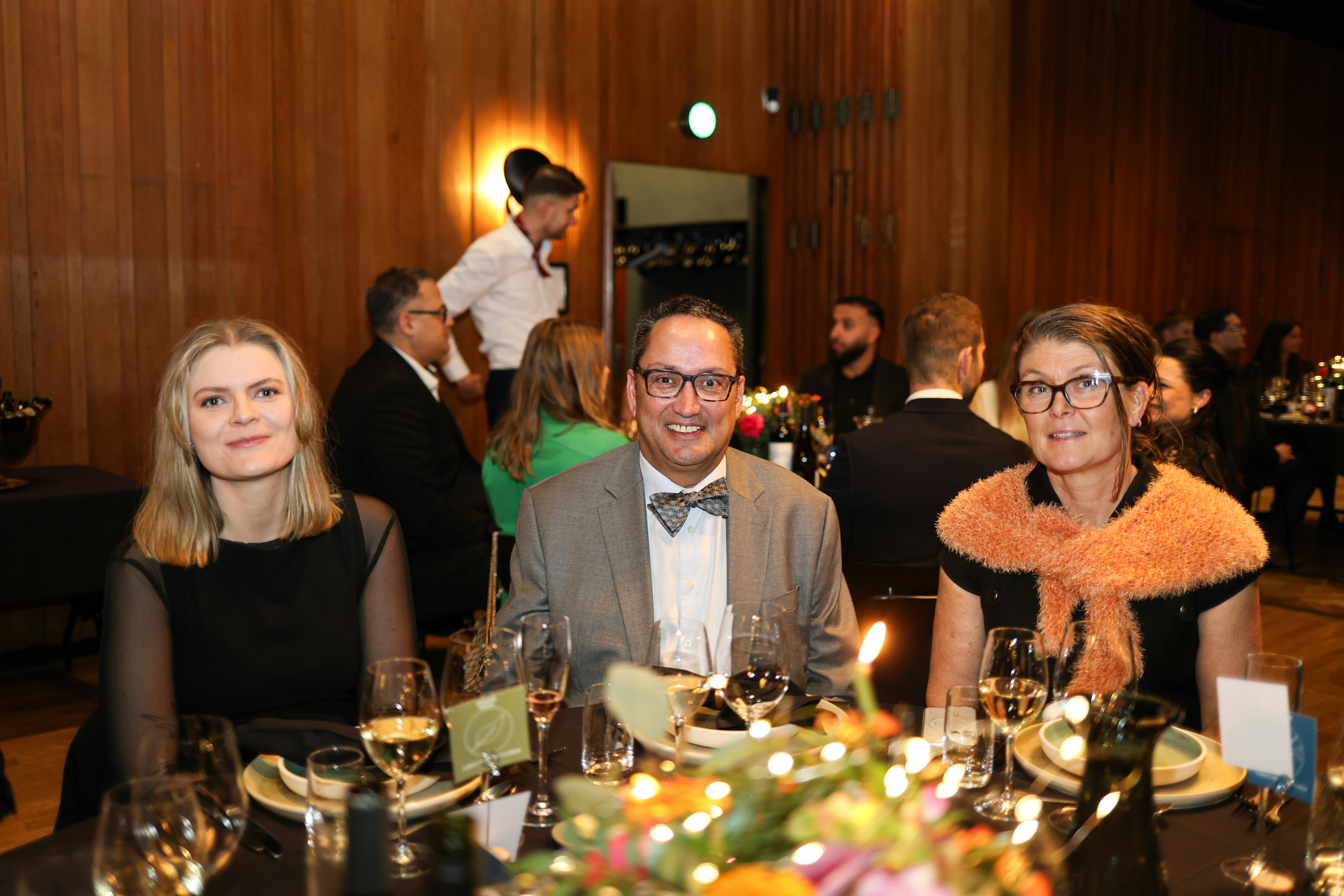 Three people seated at a formal dinner table
