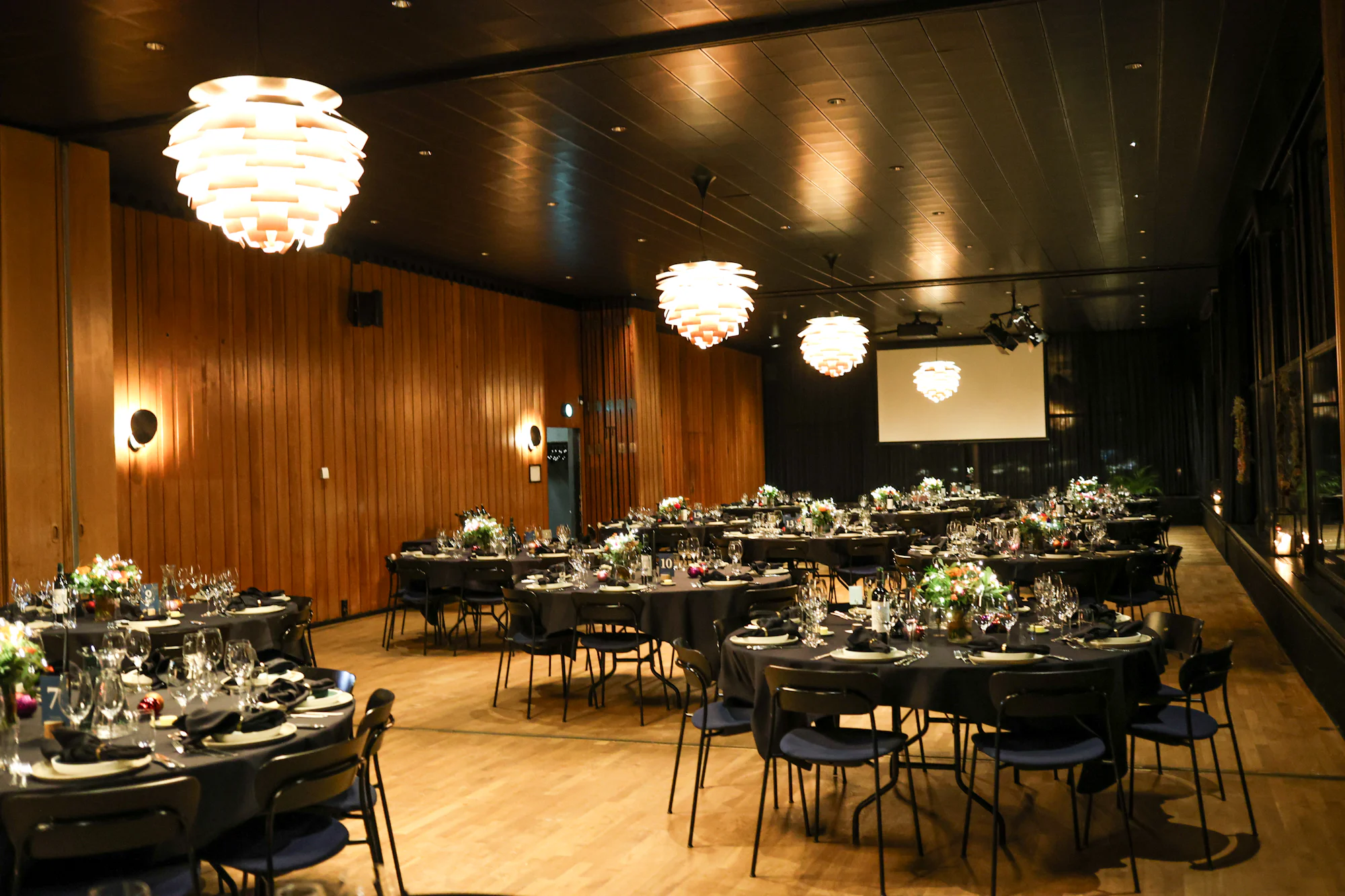 The wood-panelled Durbar Hall set with round tables beneath paper-lantern pendants