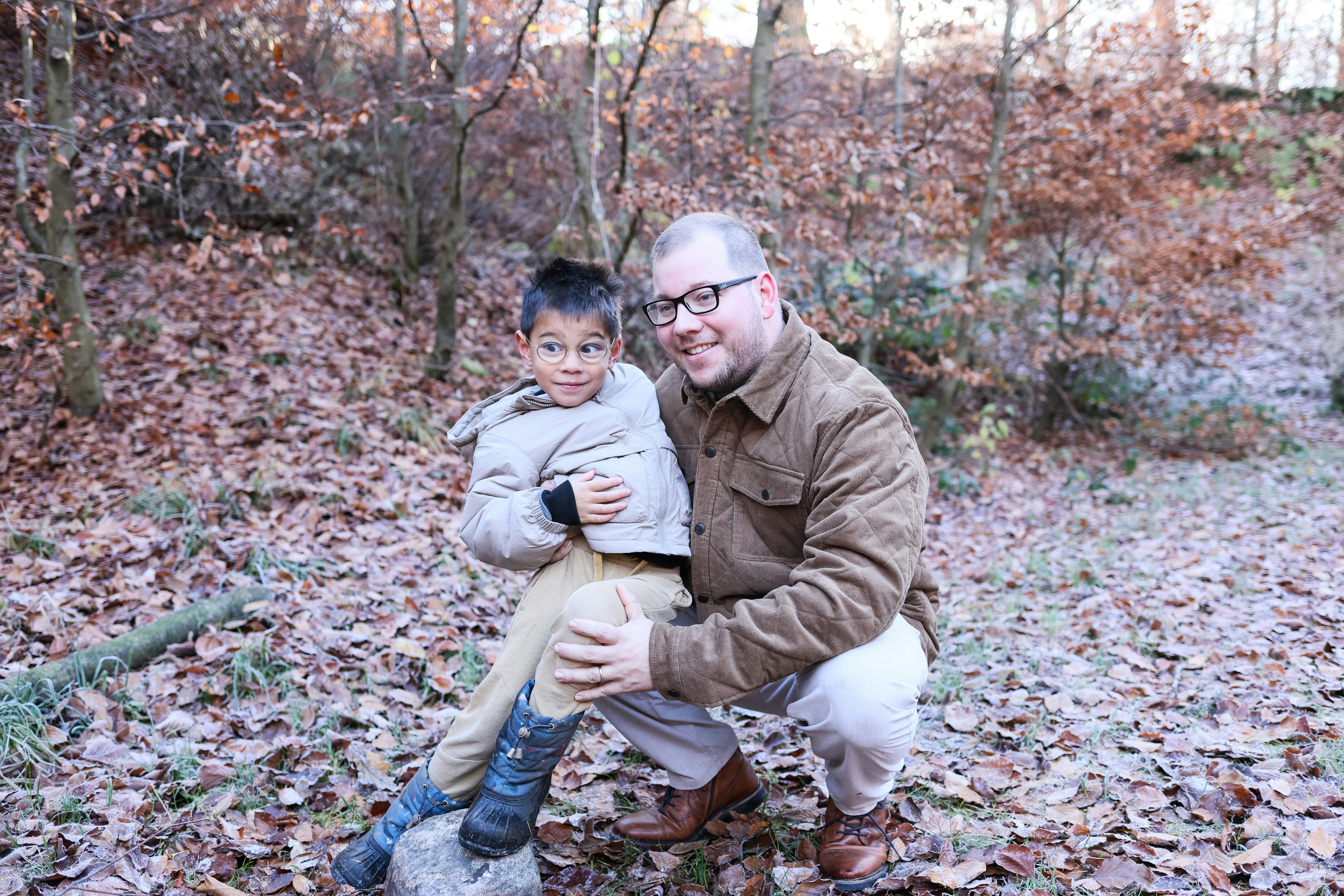 Hombre y niño posando en un entorno forestal.