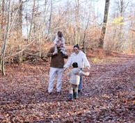 Family walking on a leaf-covered path in autumn.