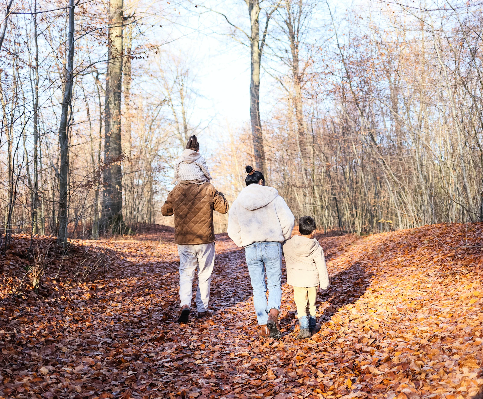 A family walking together along a path through an autumn forest