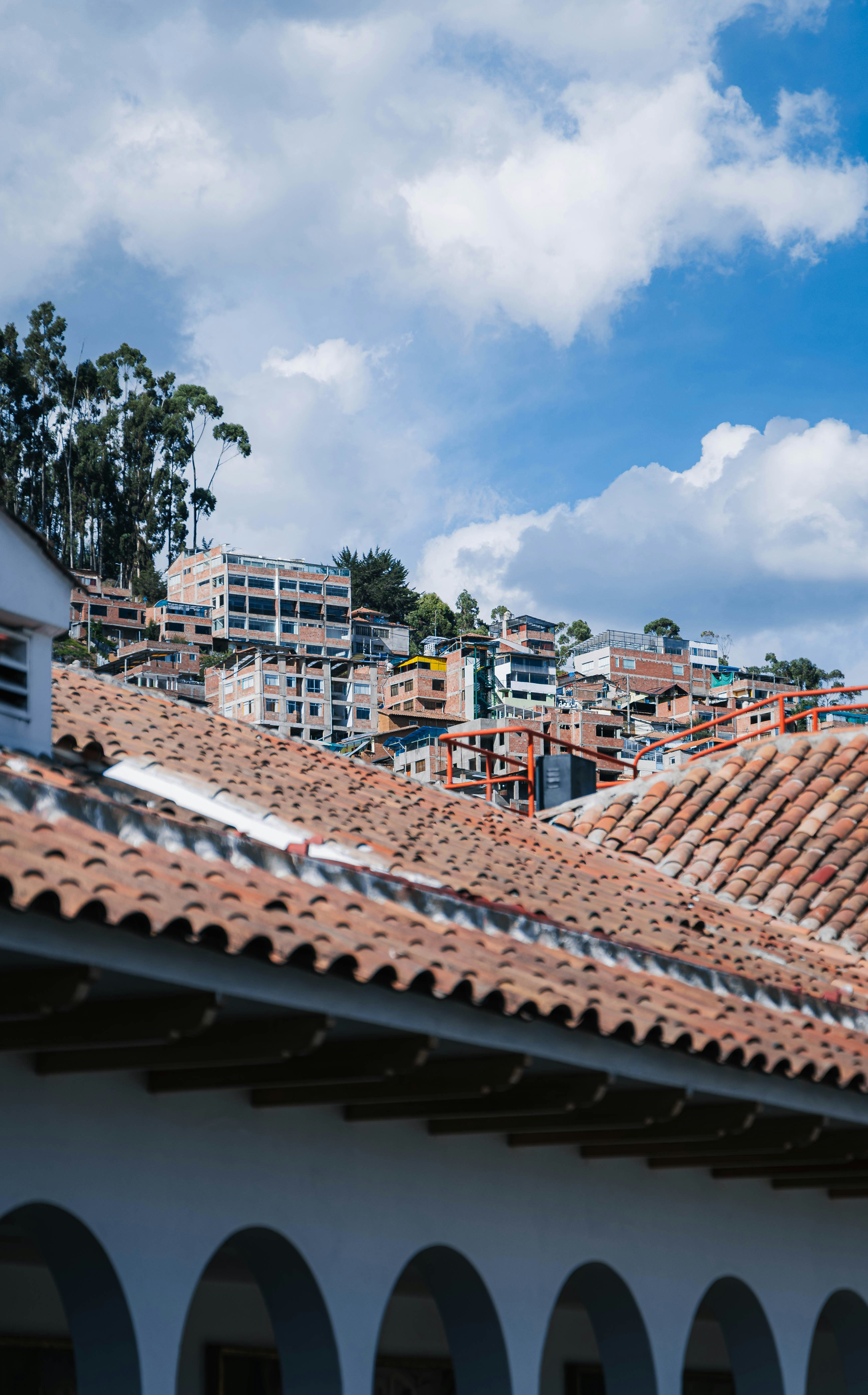 Terracotta tiled roofs with buildings on a hillside.