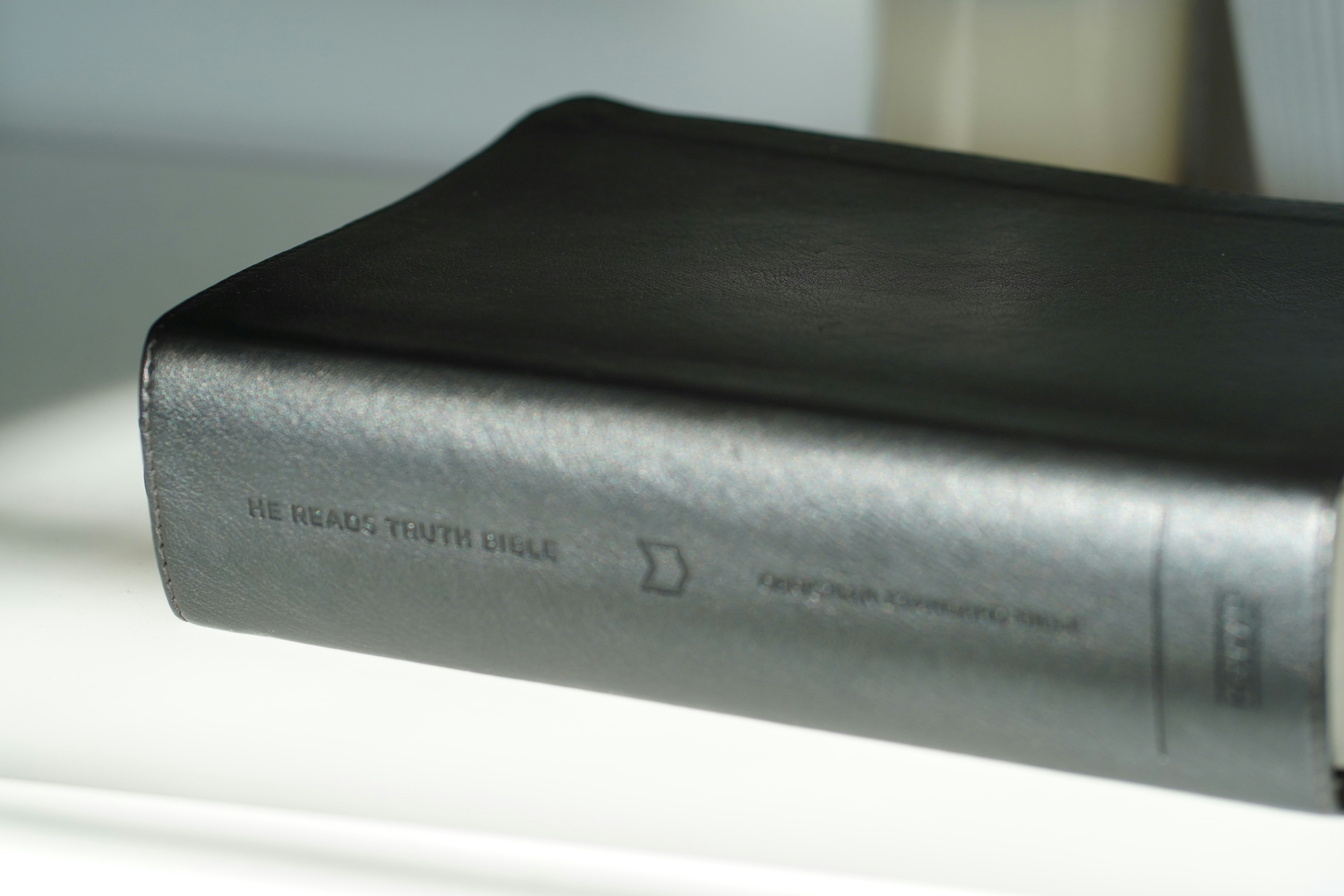 A dark leather-bound bible on a white surface.