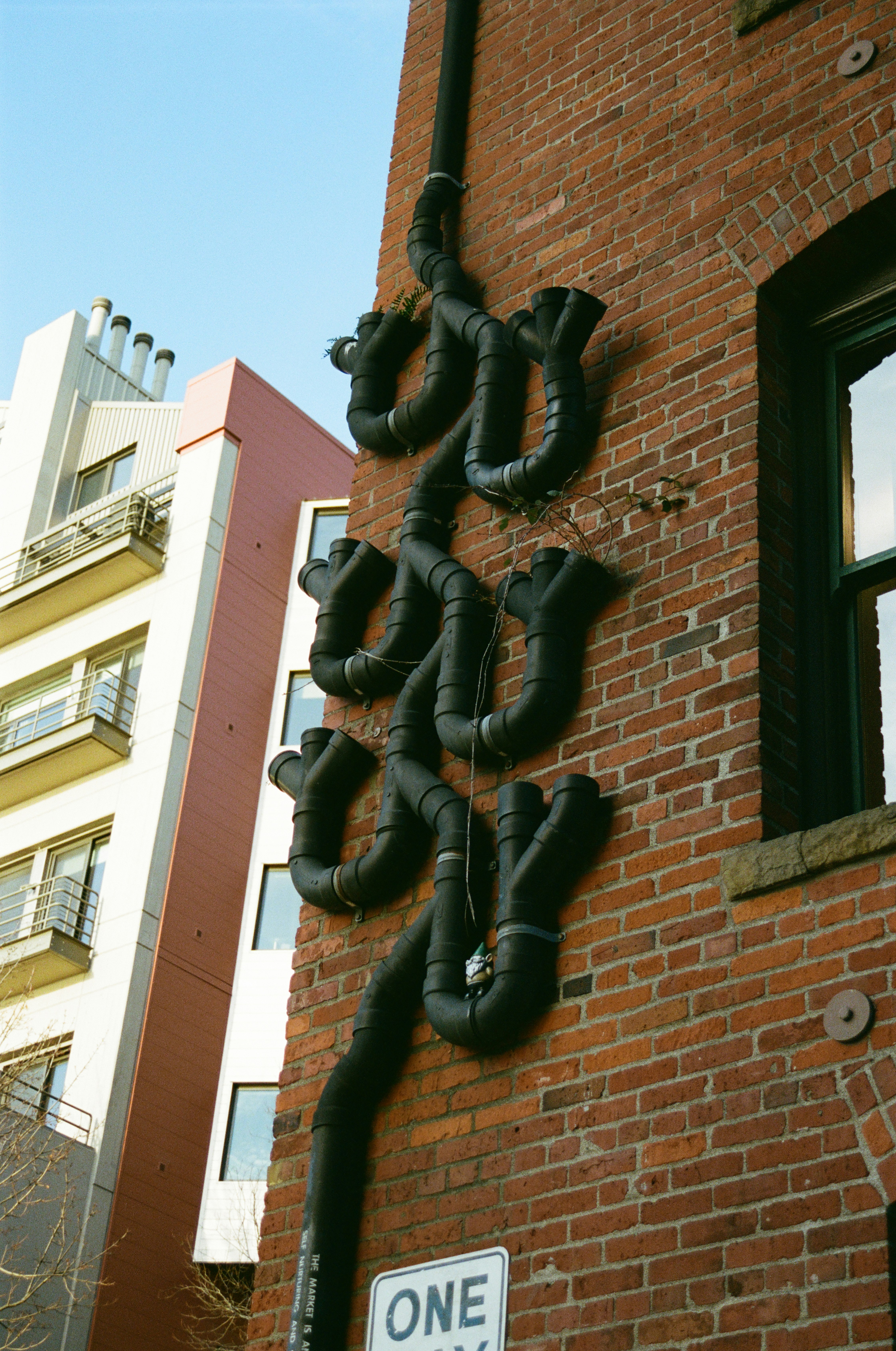 Black pipes form an artistic design on a brick wall.
