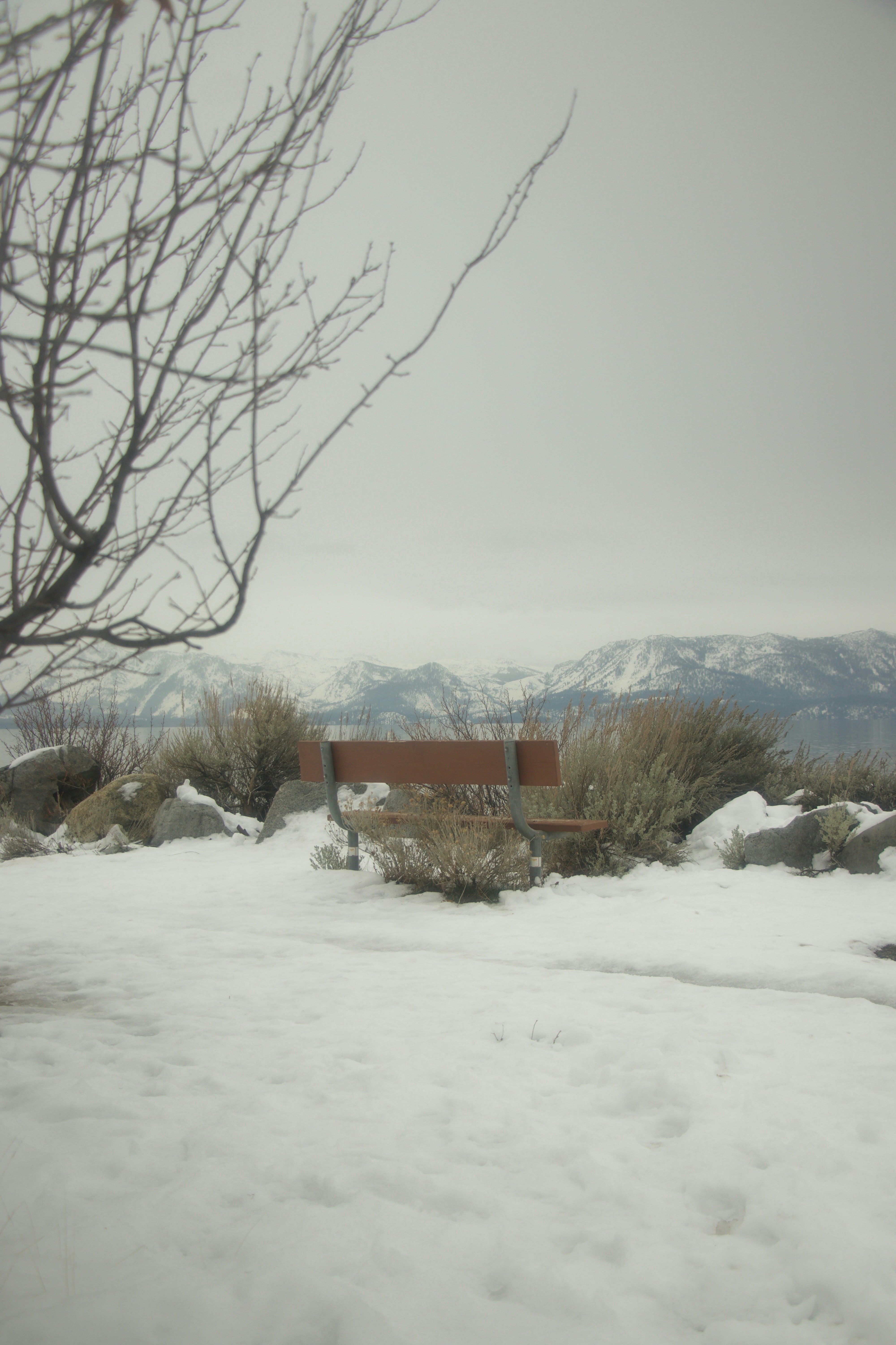 Snowy landscape with mountains and a bench