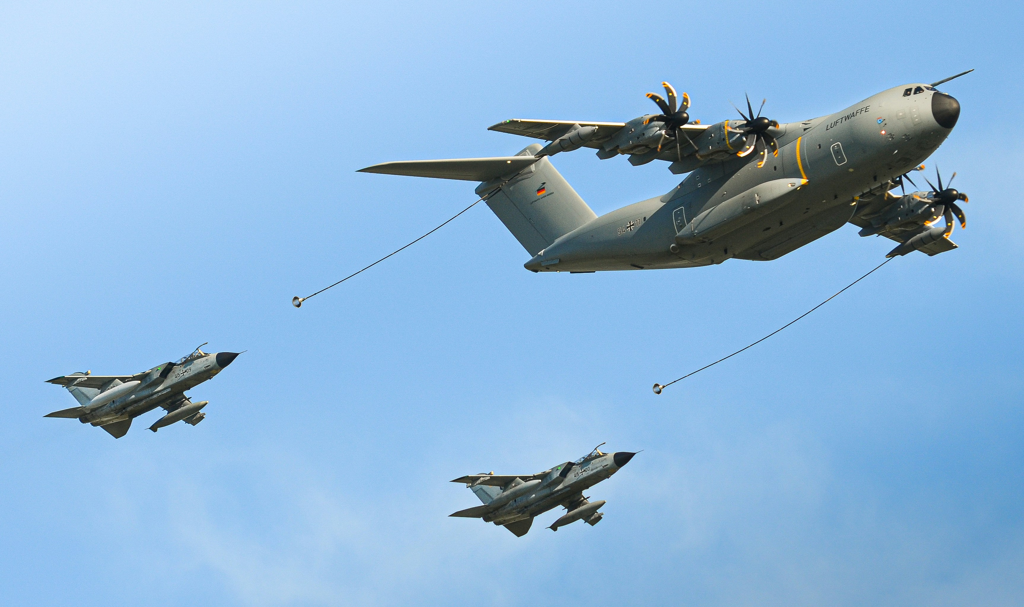Large cargo plane flying with two fighter jets below