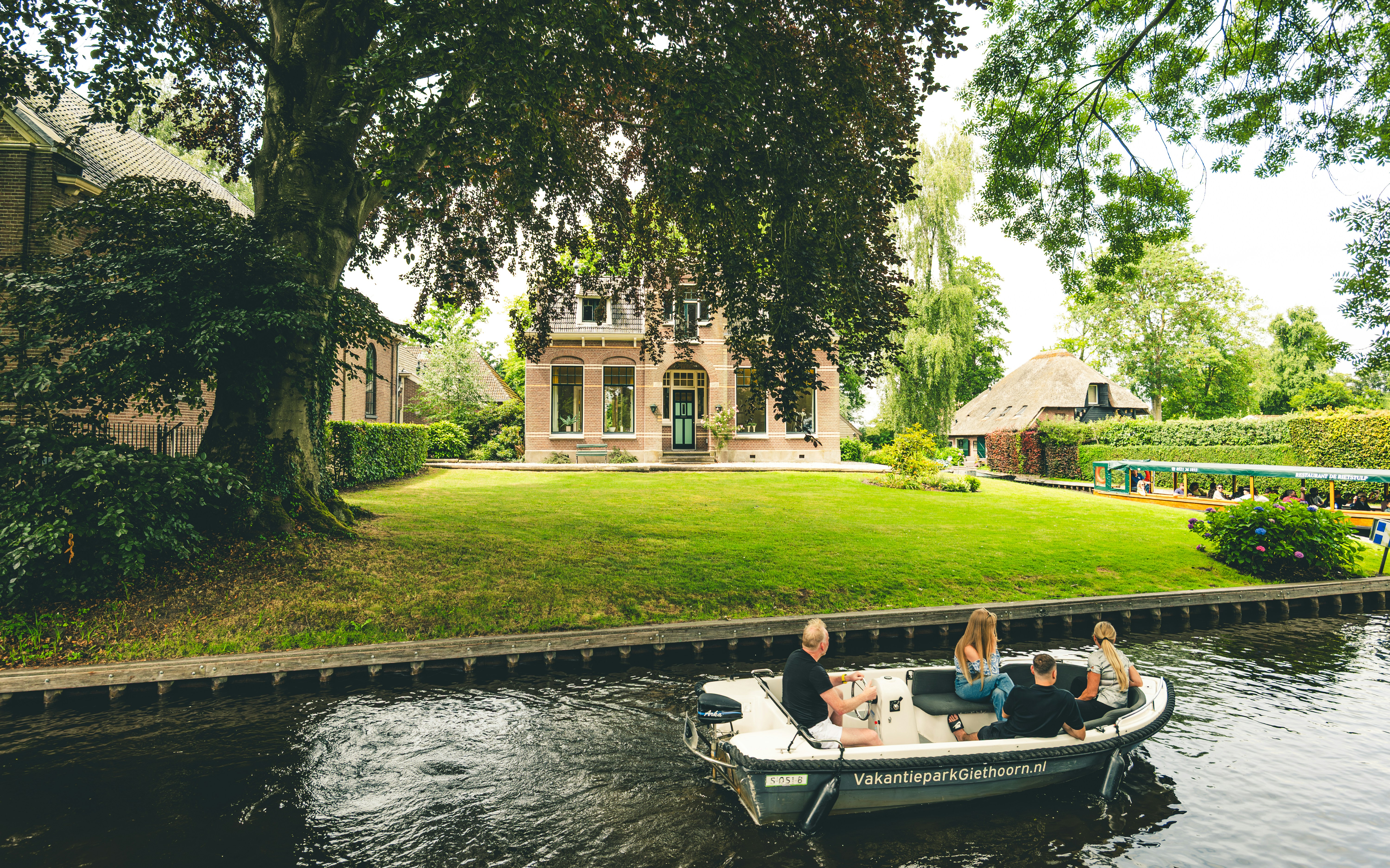 Traditional canal scene in Giethoorn featuring thatched-roof houses, wooden bridges and boats moving through the village.