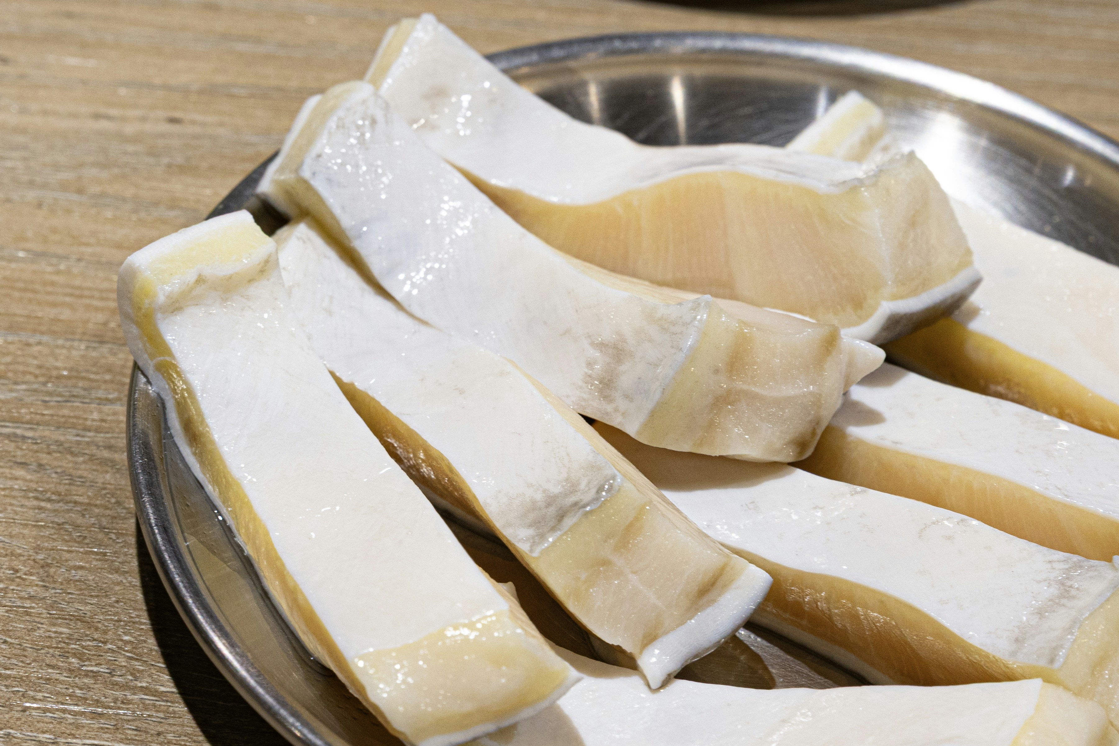 Raw king oyster mushroom slices on a metal plate
