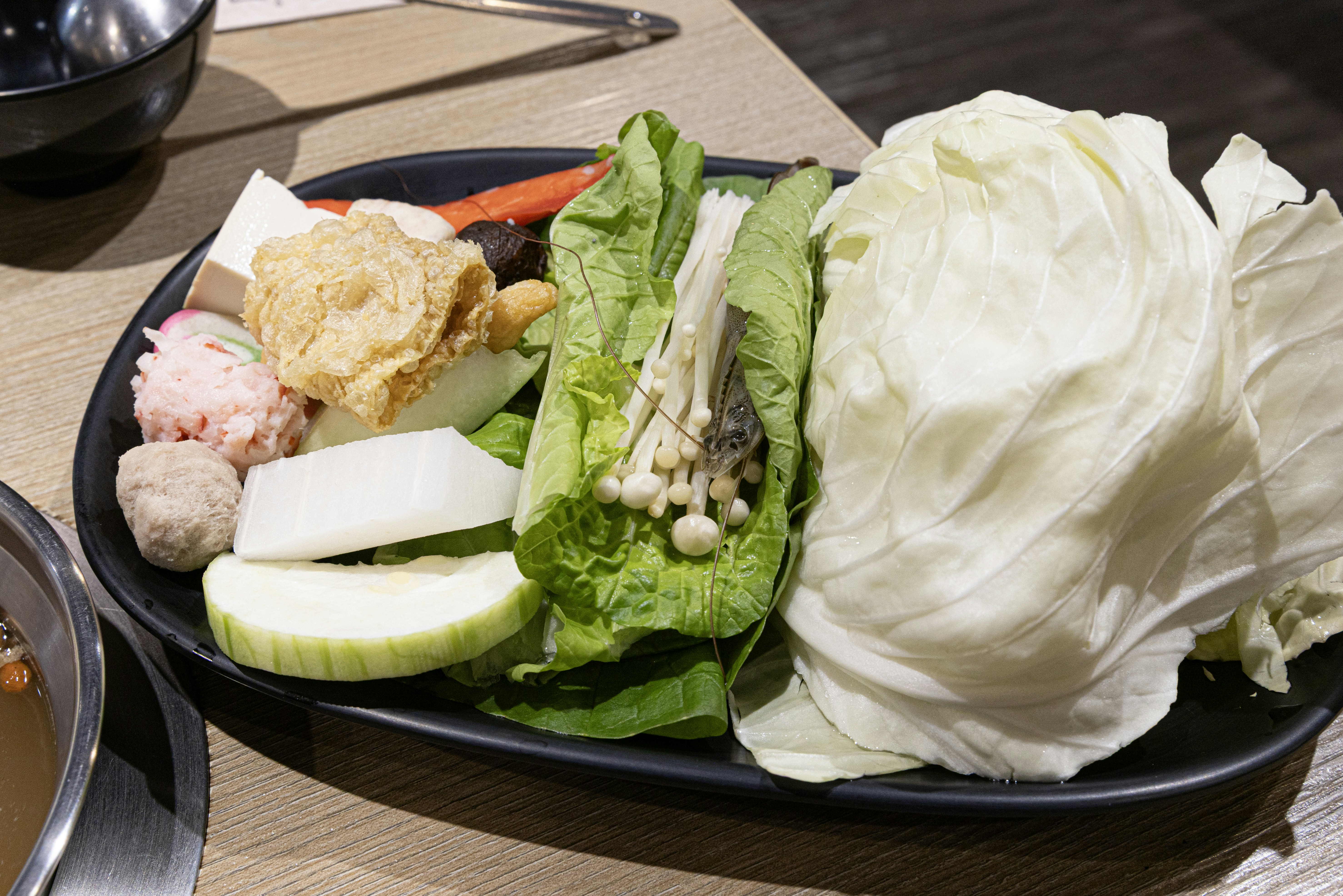A platter of fresh vegetables and ingredients for hot pot.