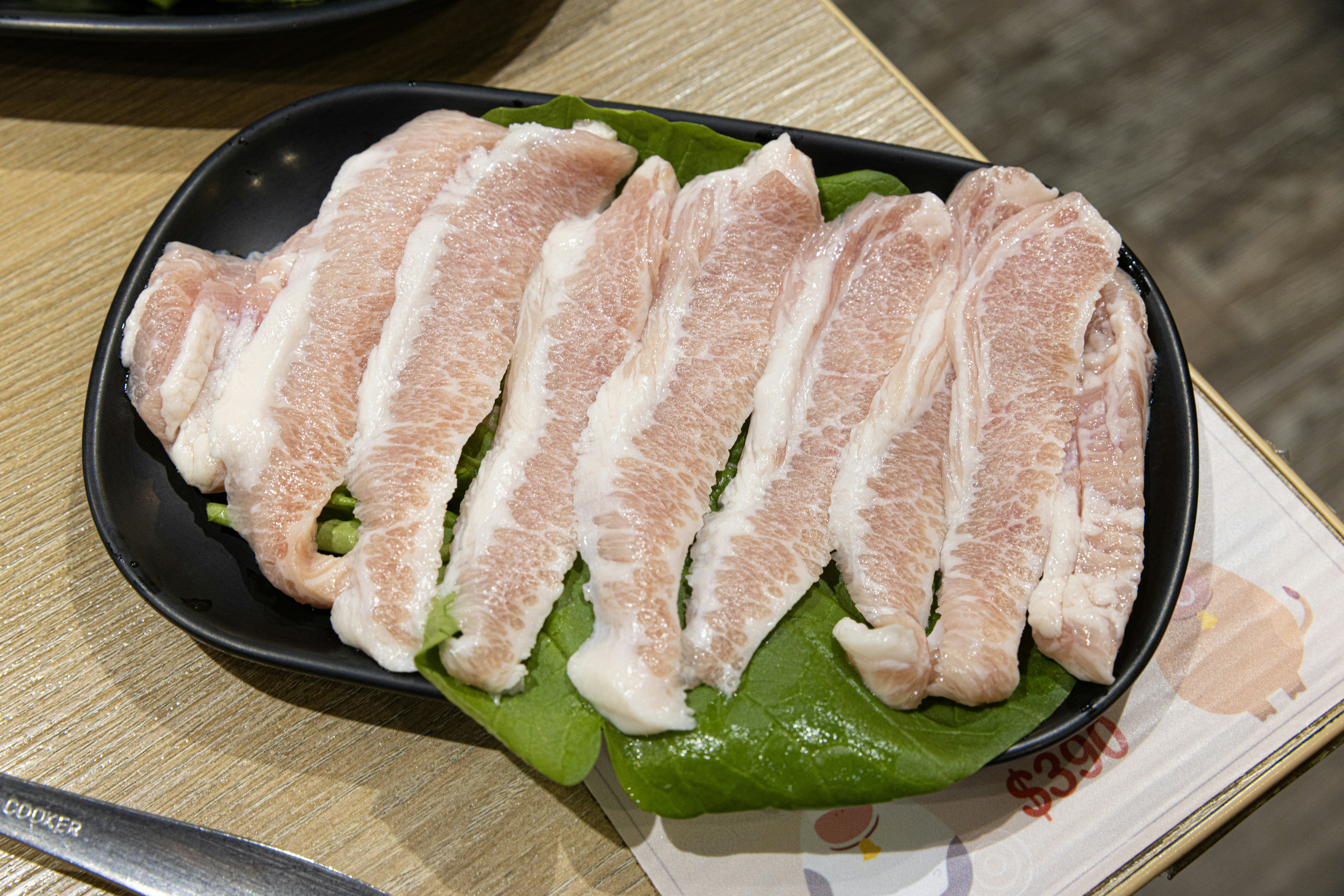 Thinly sliced raw pork belly on a plate.