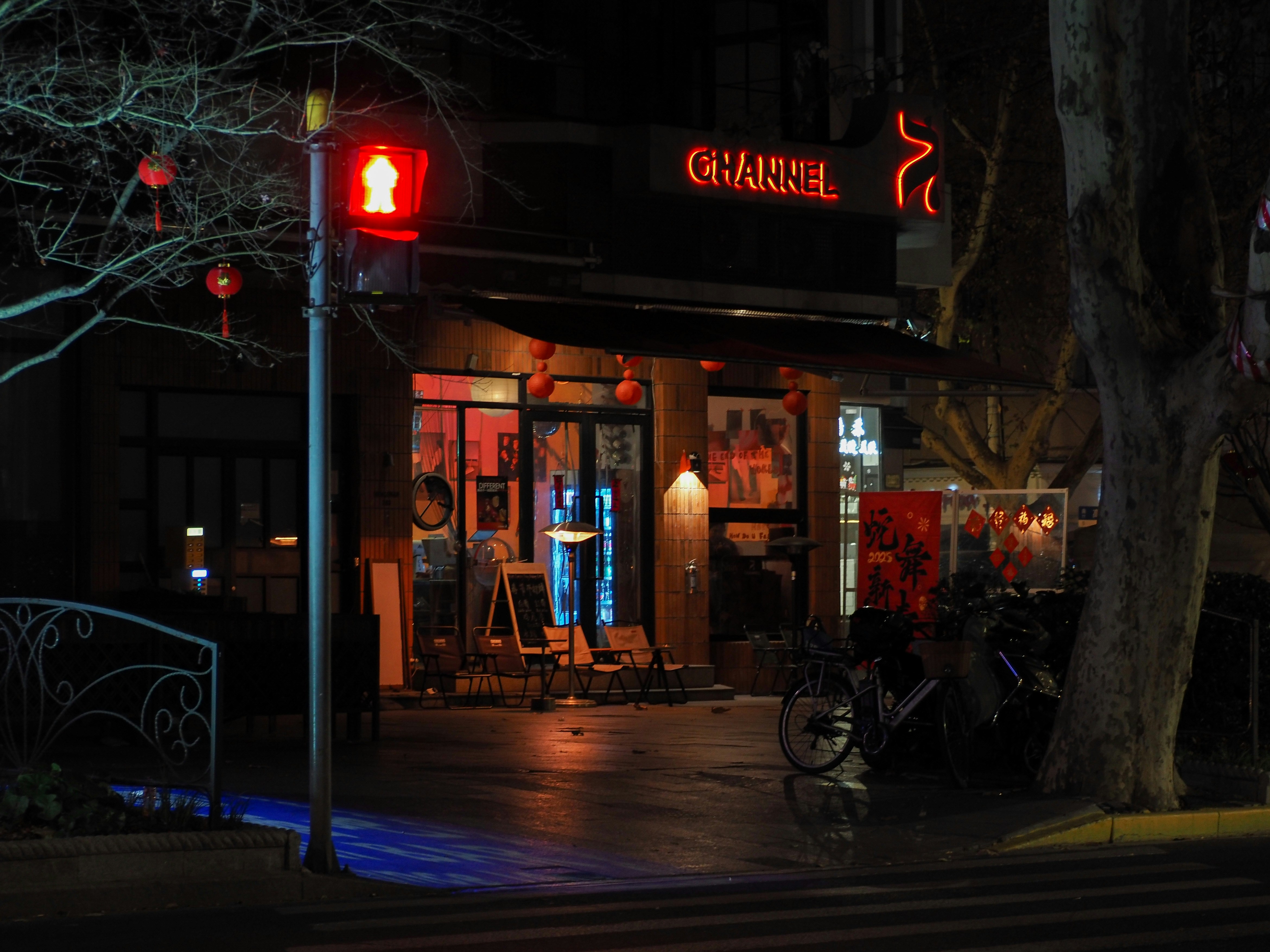 A restaurant facade at night with a red traffic light.