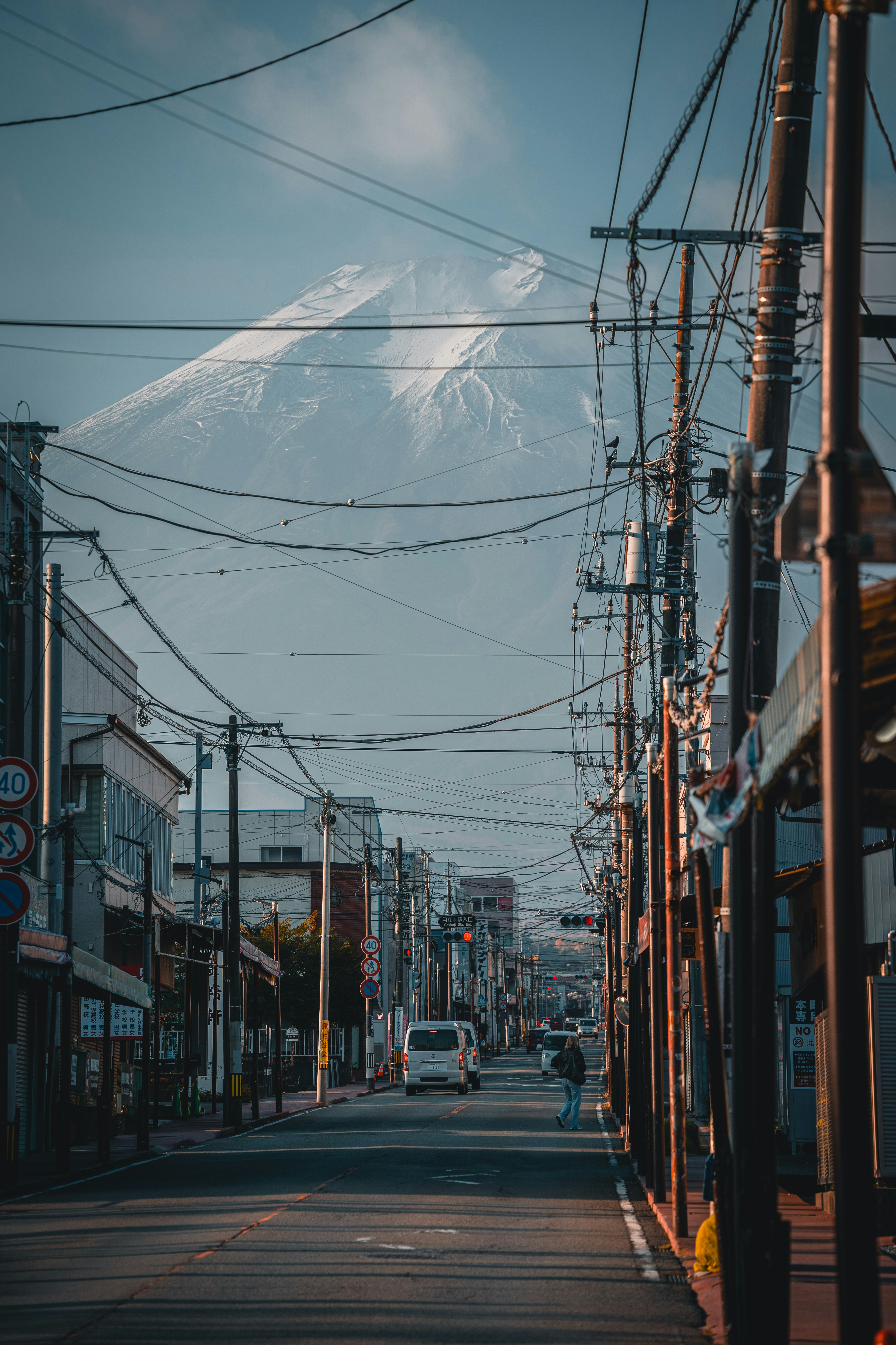 Snow-capped mountain looms over a street with power lines