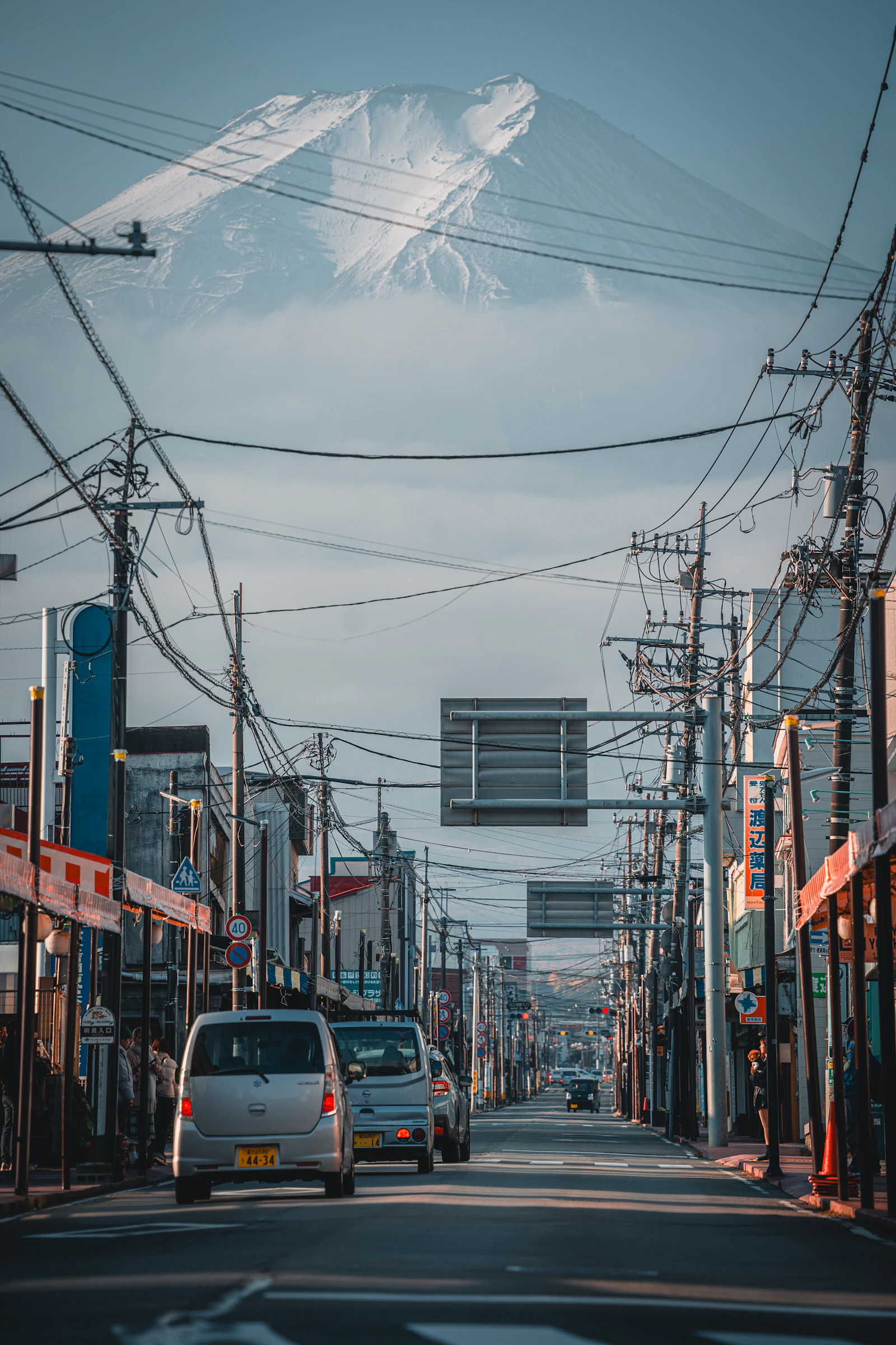 Cars travel along a Japanese street below Mount Fuji