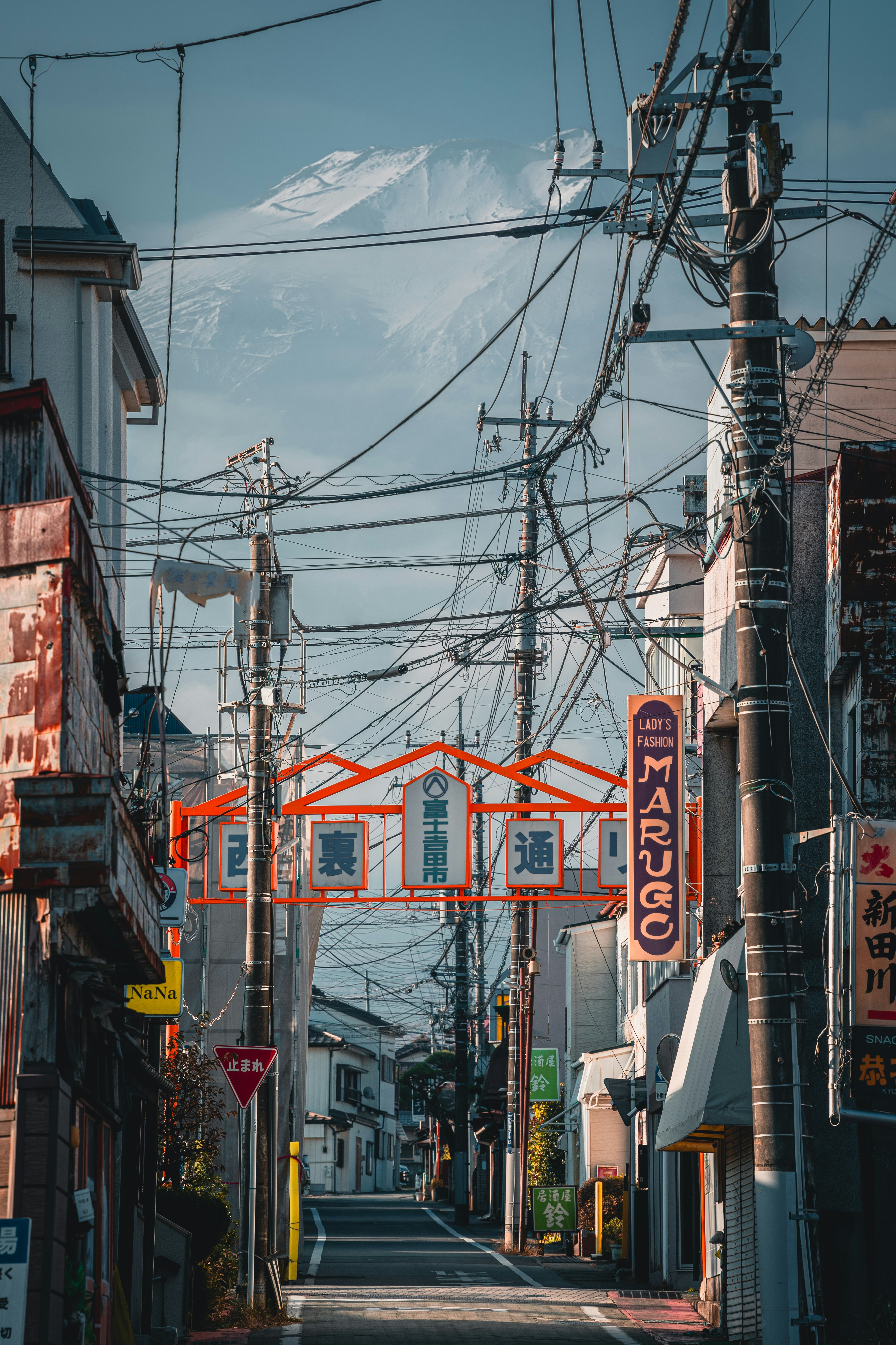 A street with power lines leading to a distant mountain.