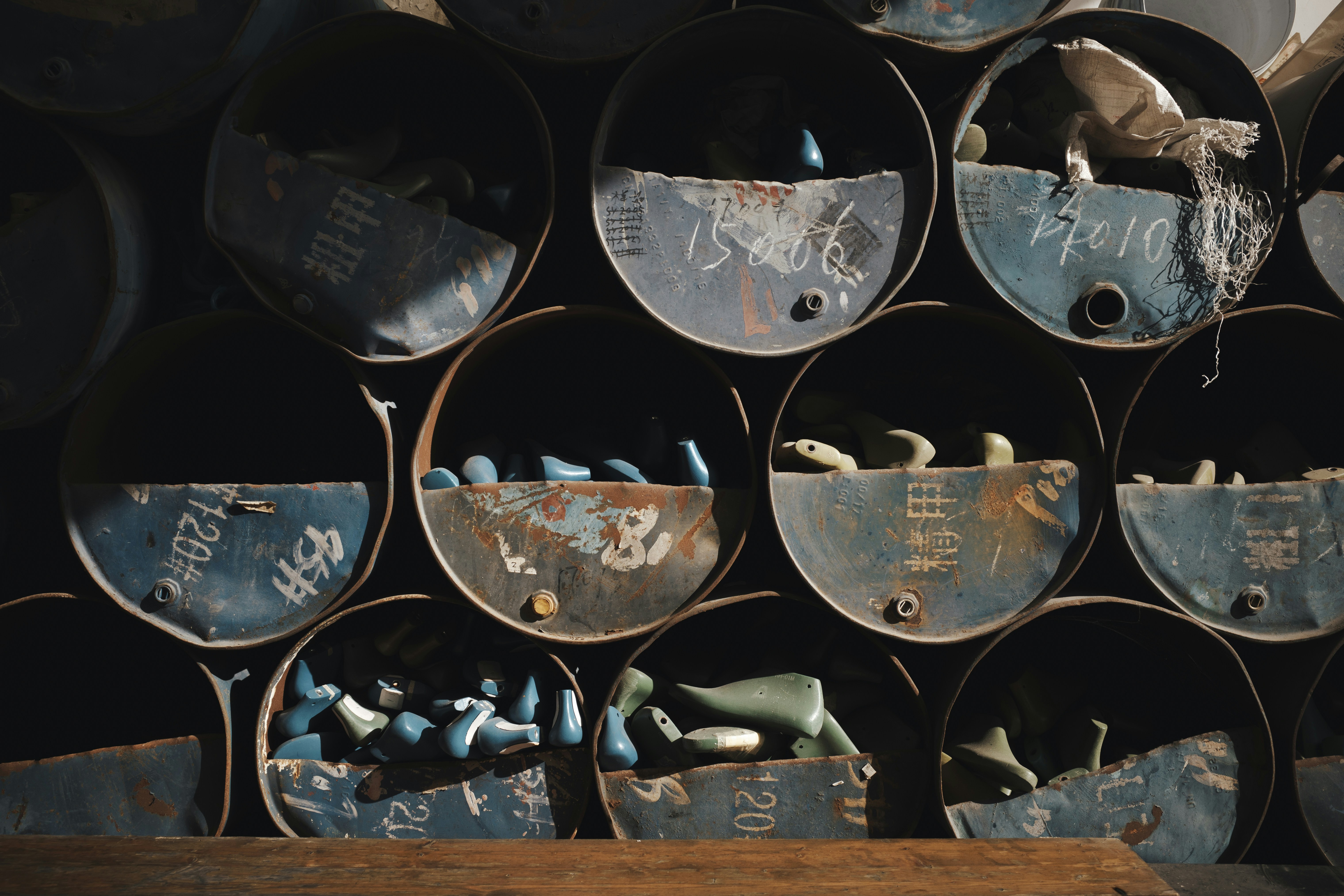 Stacked rusty metal barrels with blue objects inside