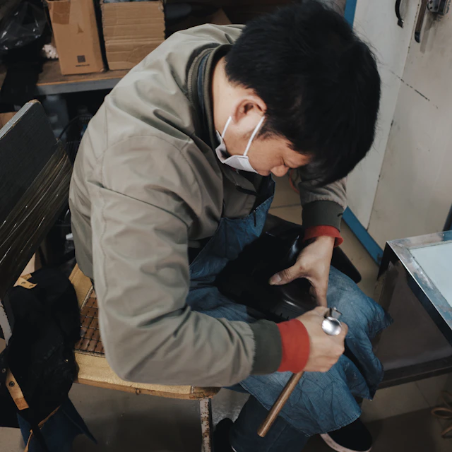 Man working on a shoe at a bench in a small workshop
