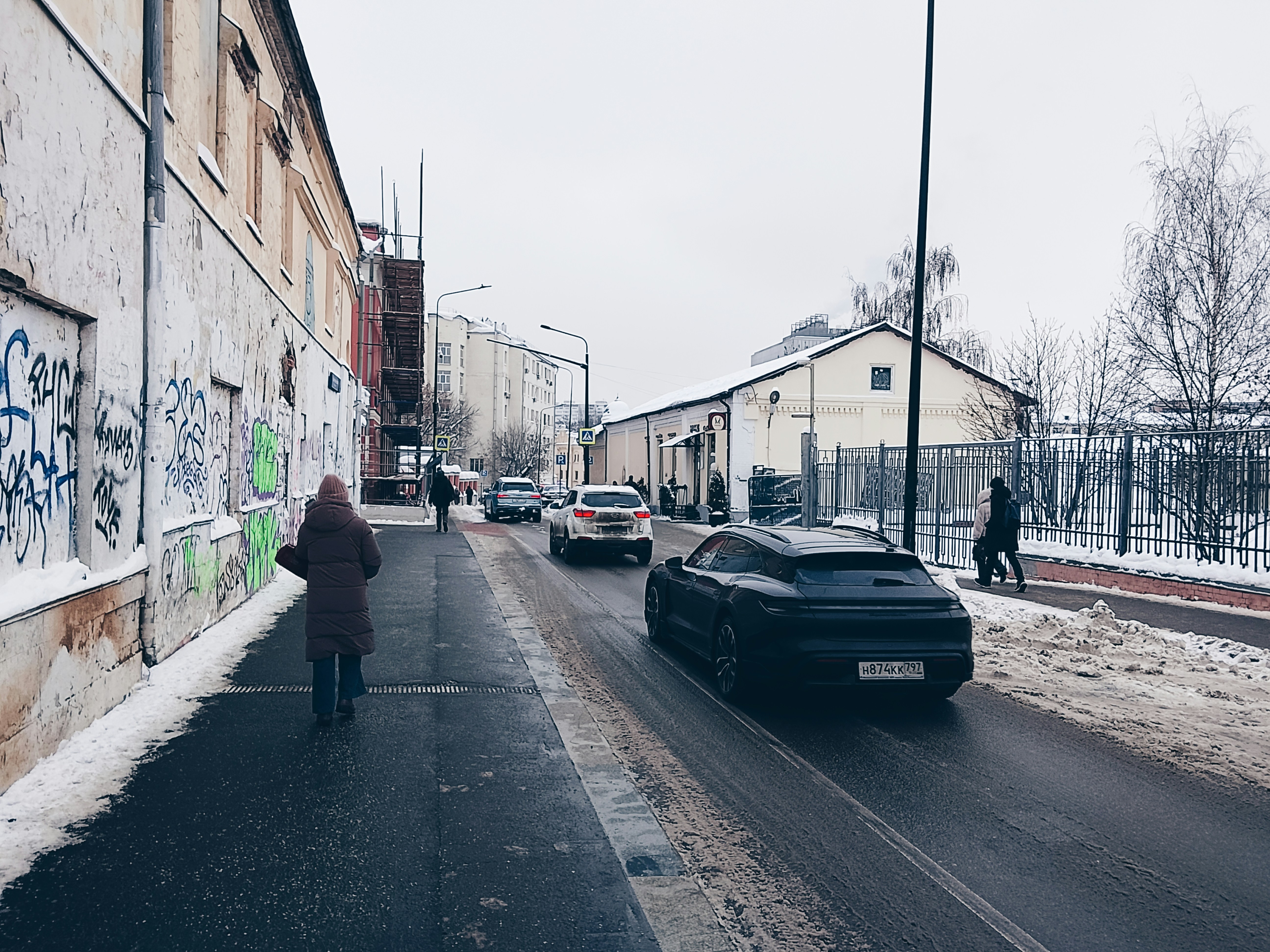 雪に覆われた通りを走る車と建物、そして人々