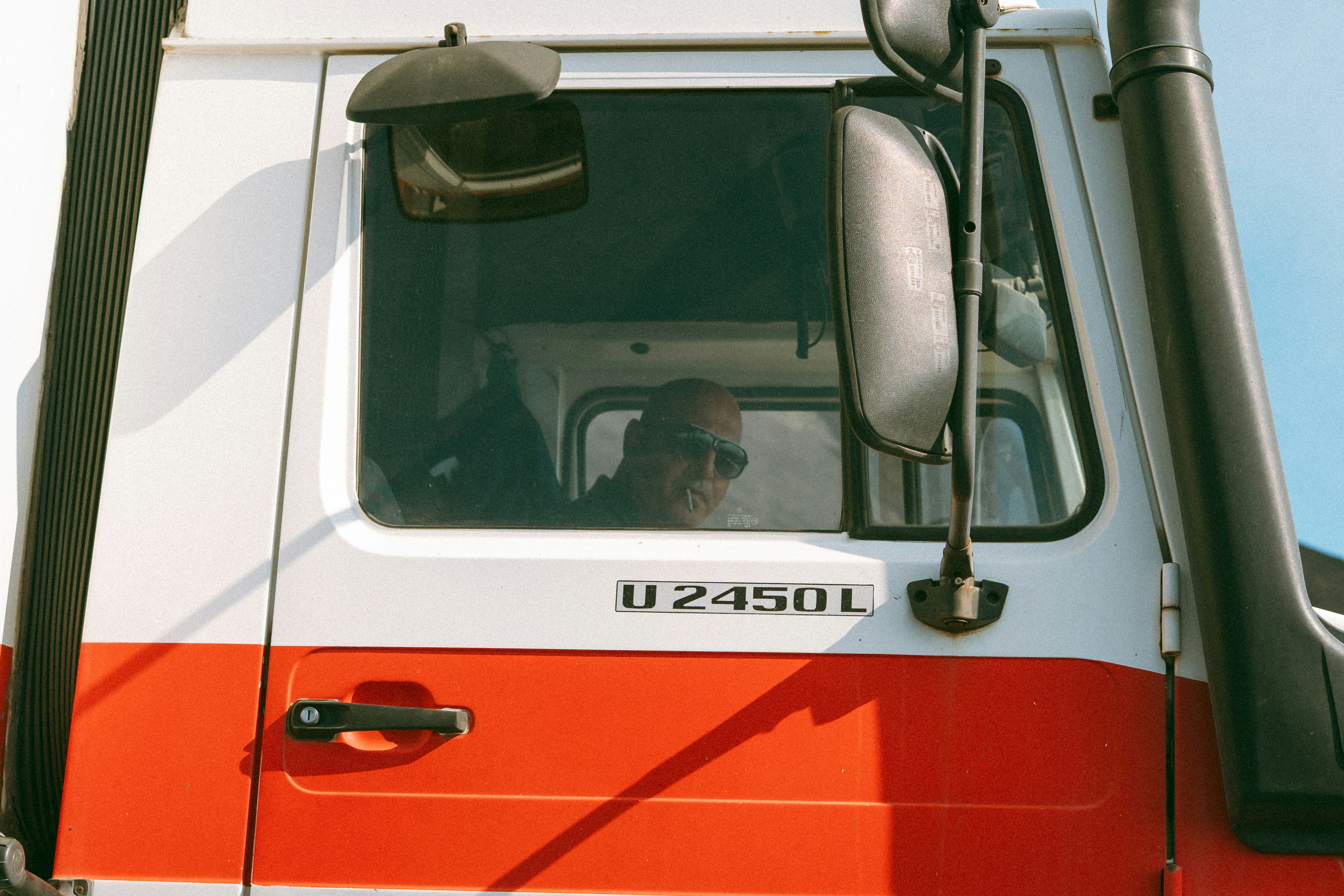 Driver in a truck cab with large side mirror