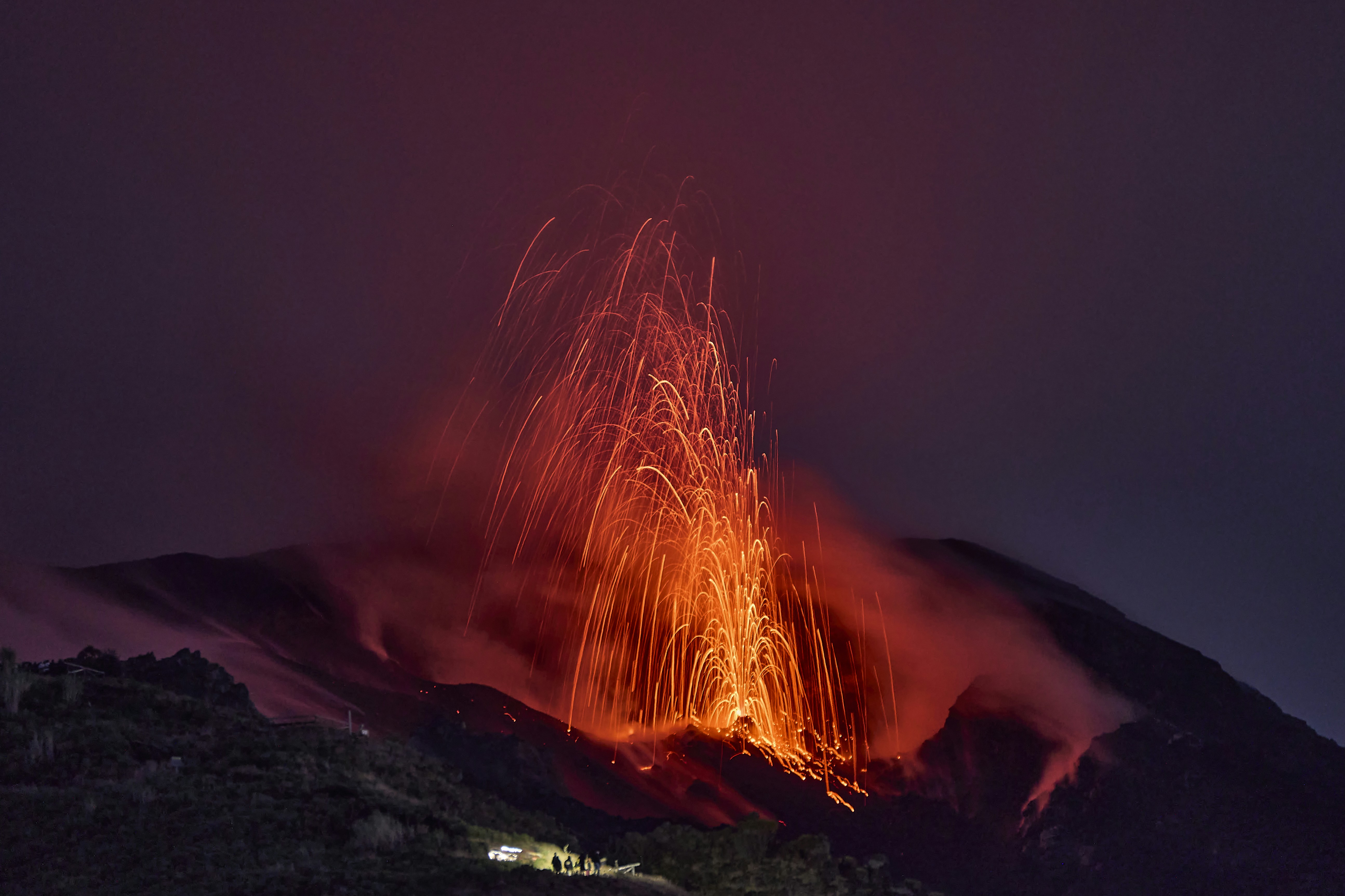 Volcano erupting glowing lava and ash at night