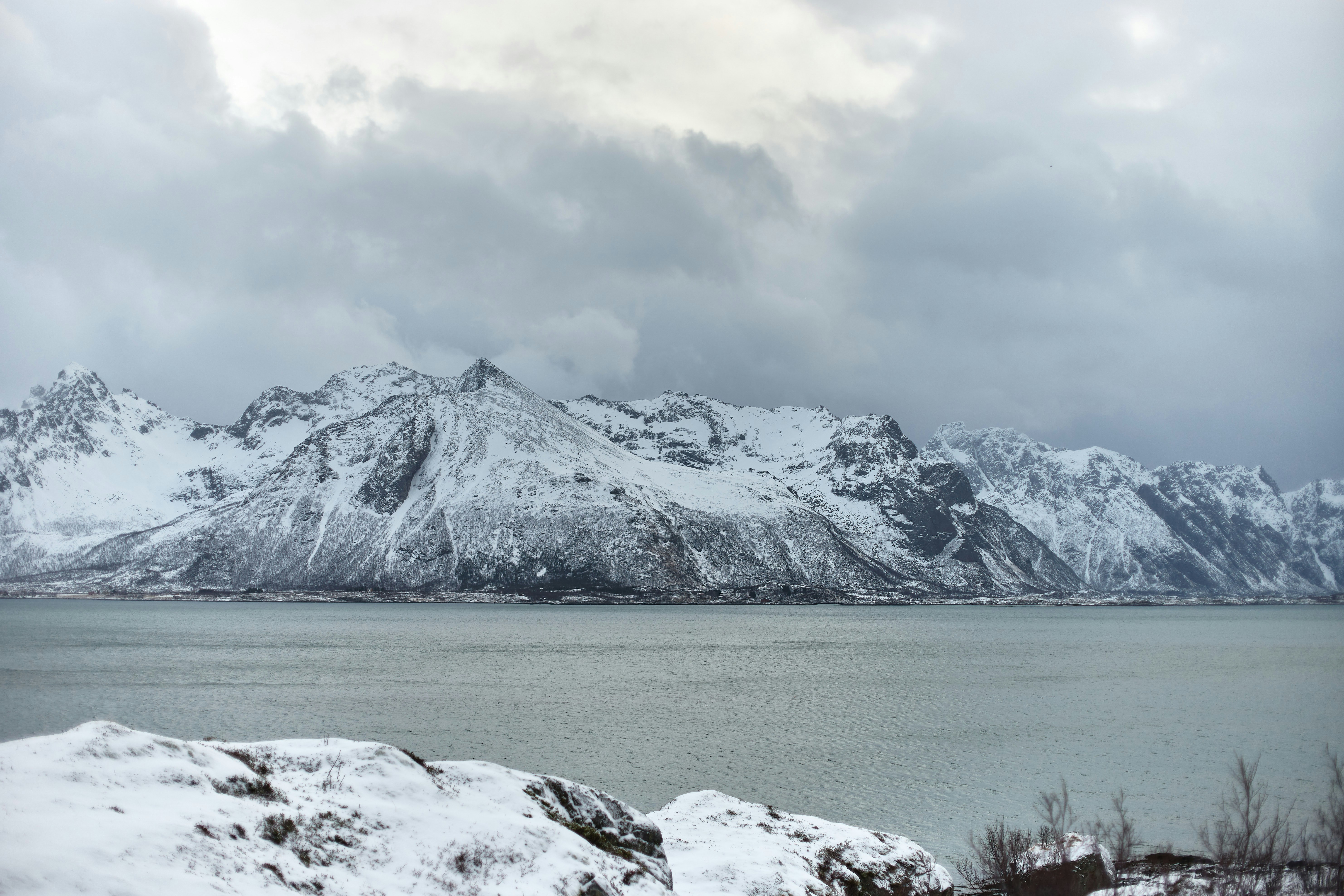 Snow-covered mountains rise above a calm body of water.