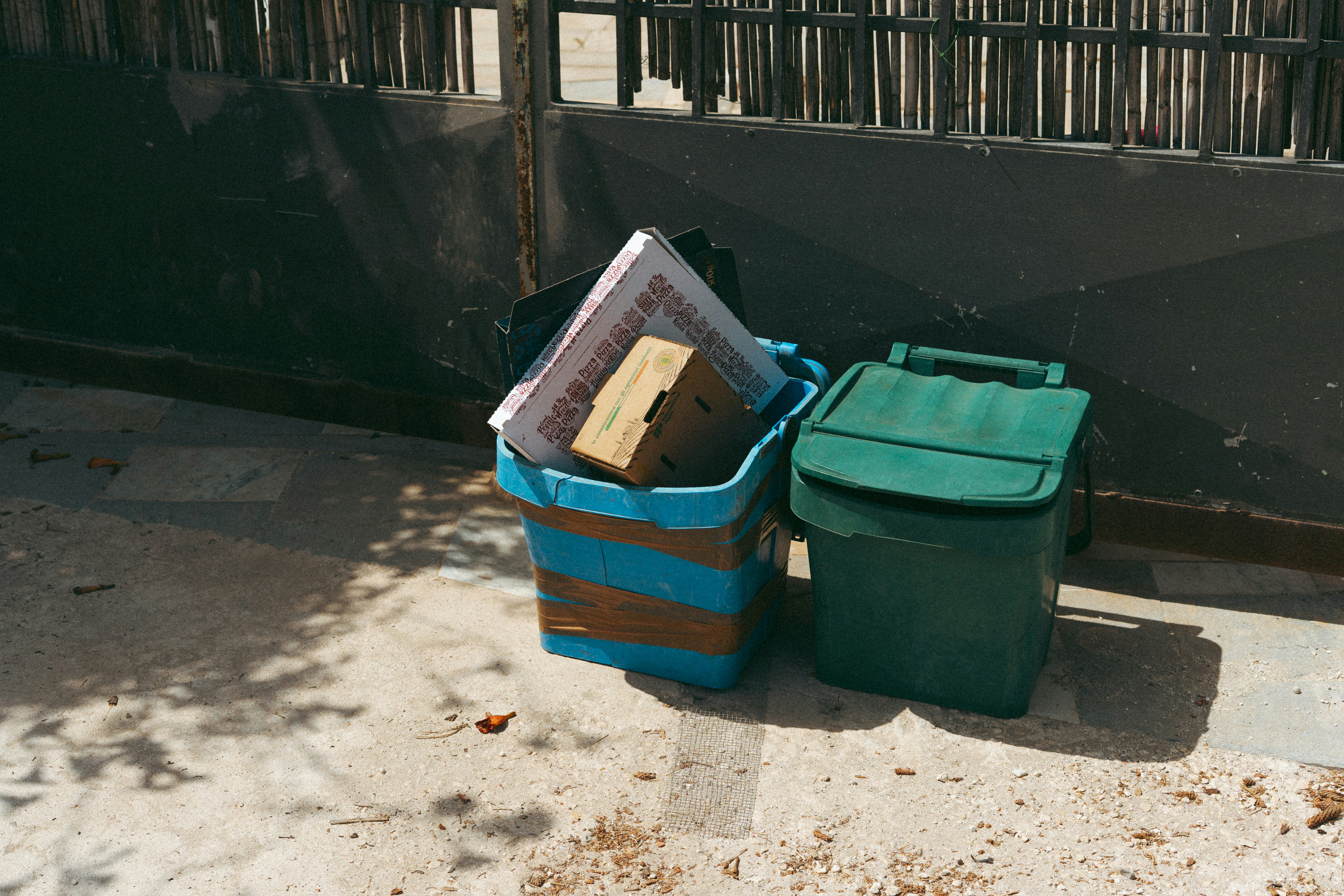 Two bins, one blue and one green, filled with trash.