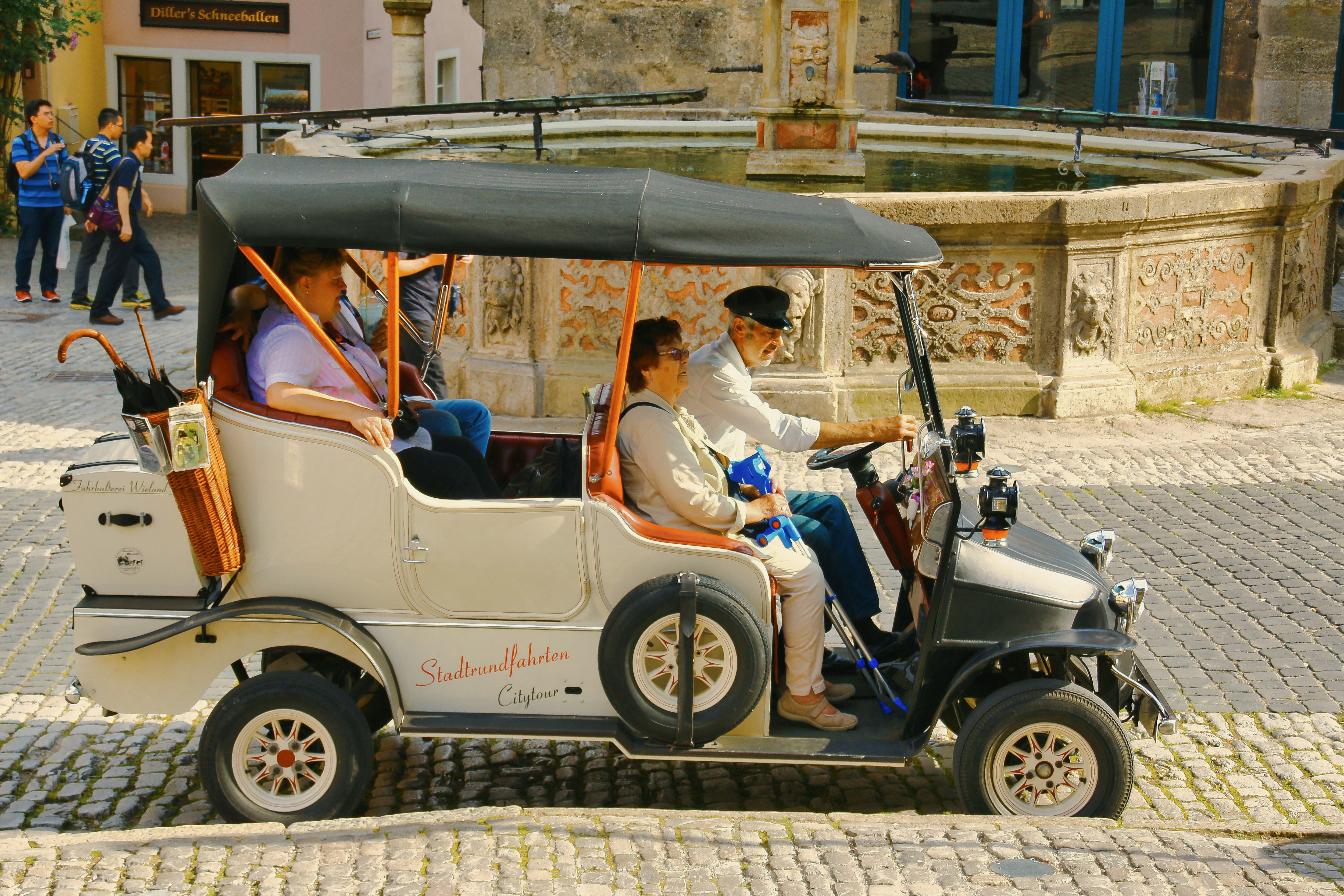 People ride in a vintage open-air car
