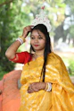 A woman in a yellow sari with traditional headwear.