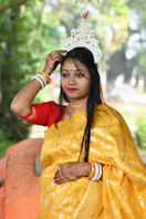 A woman in a yellow sari with traditional headwear.