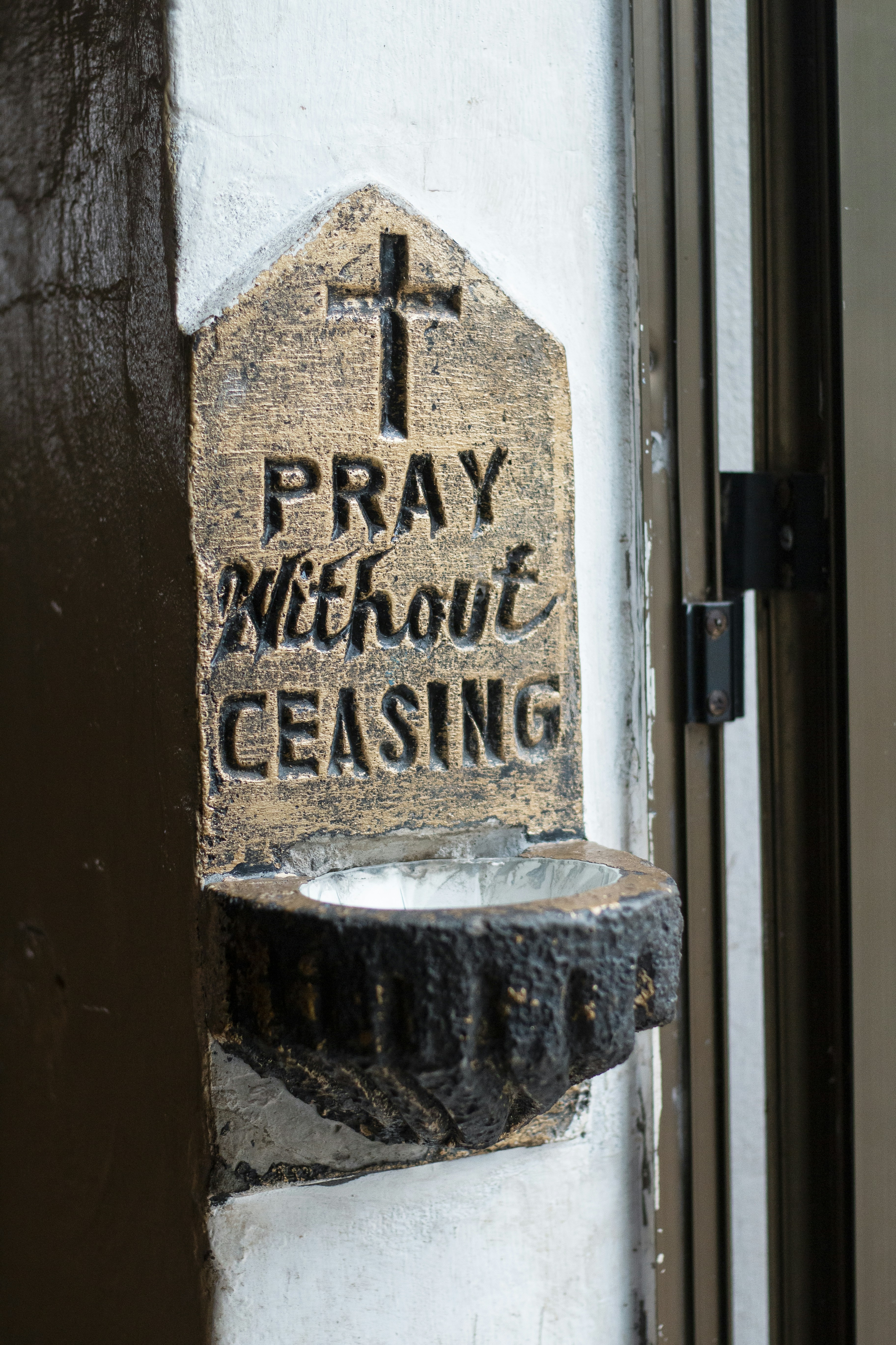 A holy water font with "pray without ceasing" inscription.