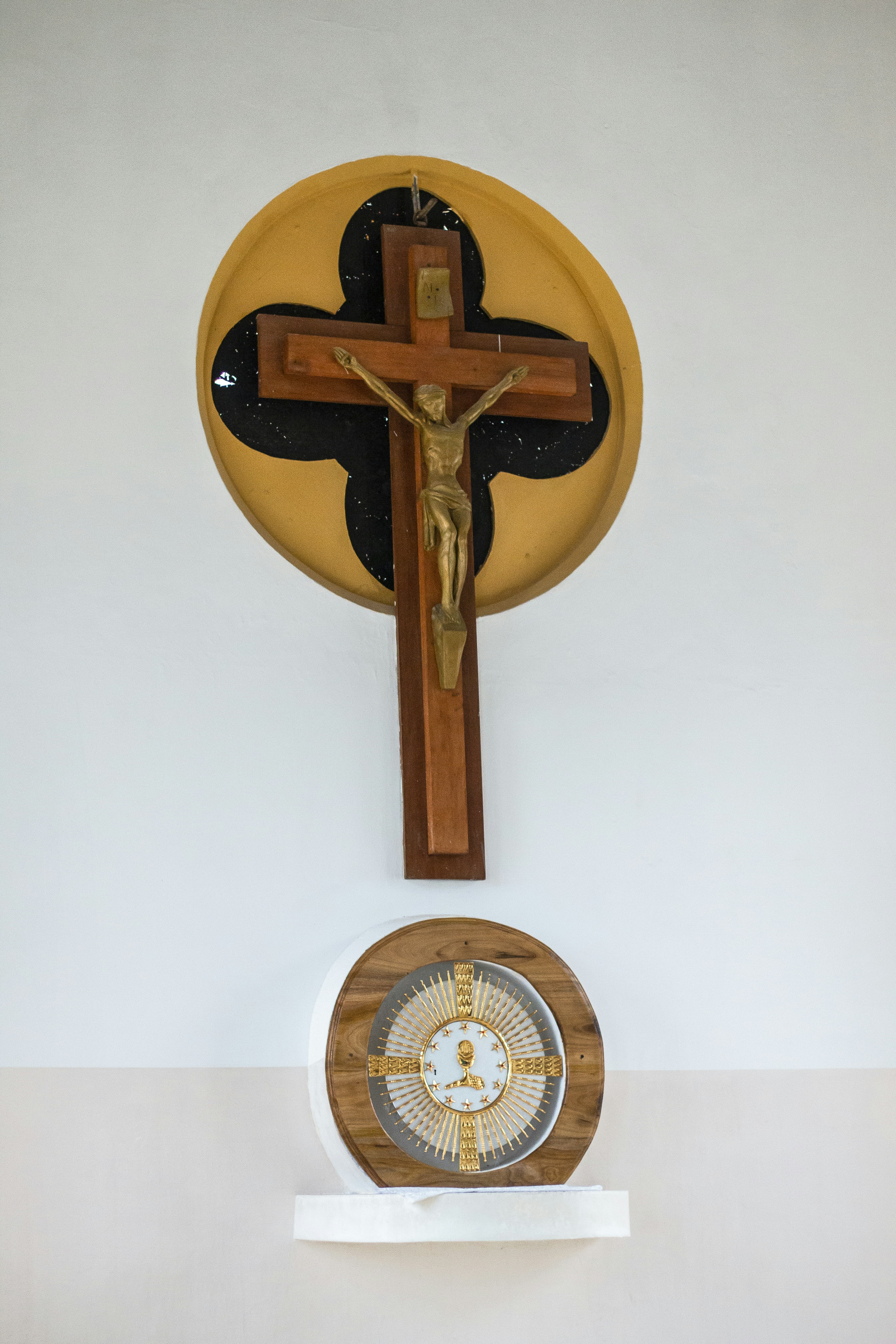 Crucifixo de madeira com Jesus e um medalhão religioso.