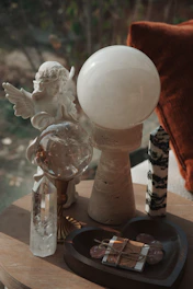 An angel statue with crystals and a clear orb.