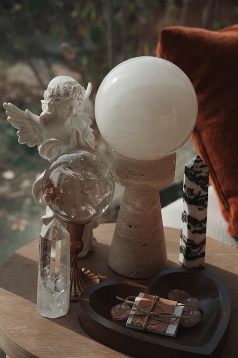 An angel statue with crystals and a clear orb.