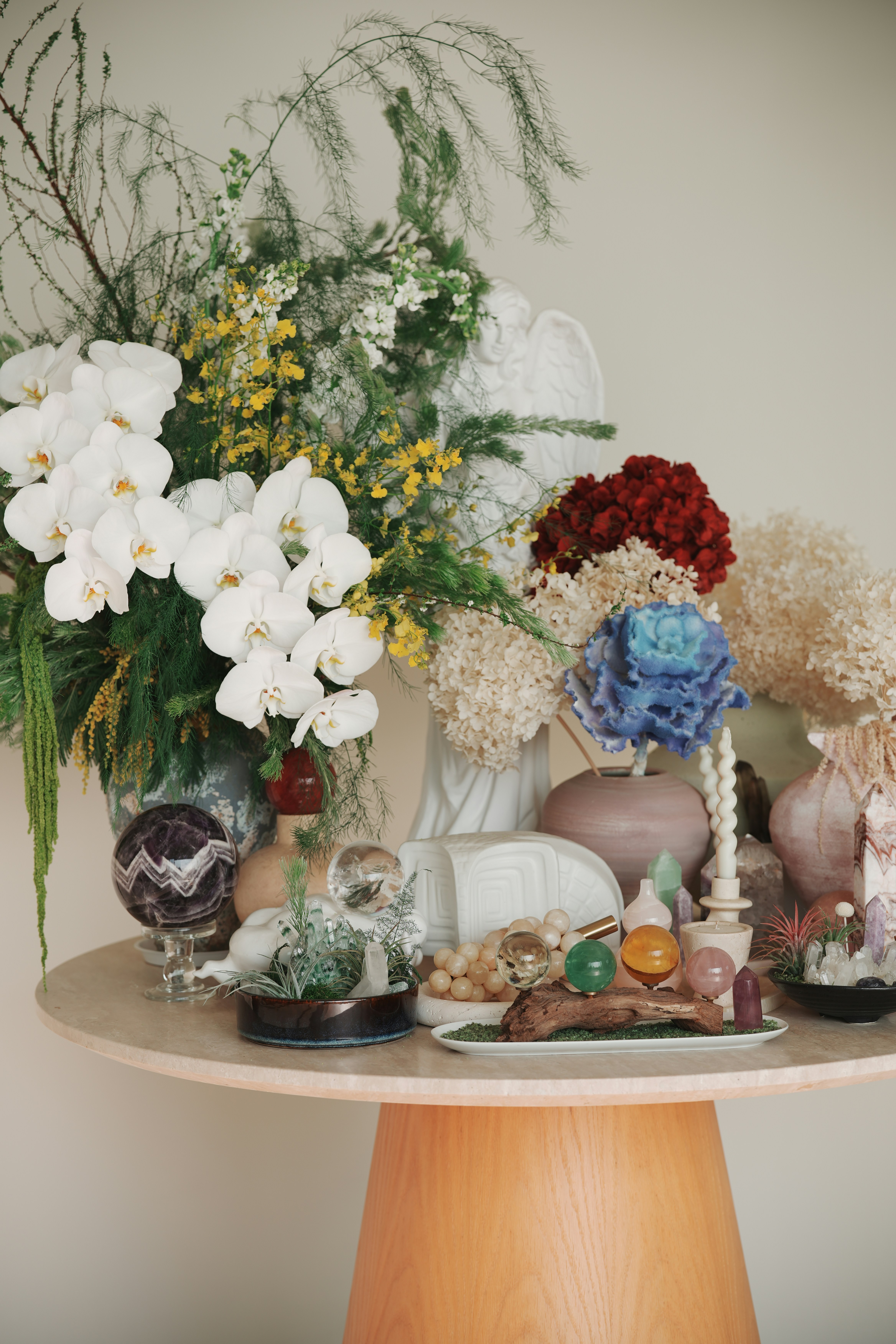 A table with flowers, crystals, and decorative objects.