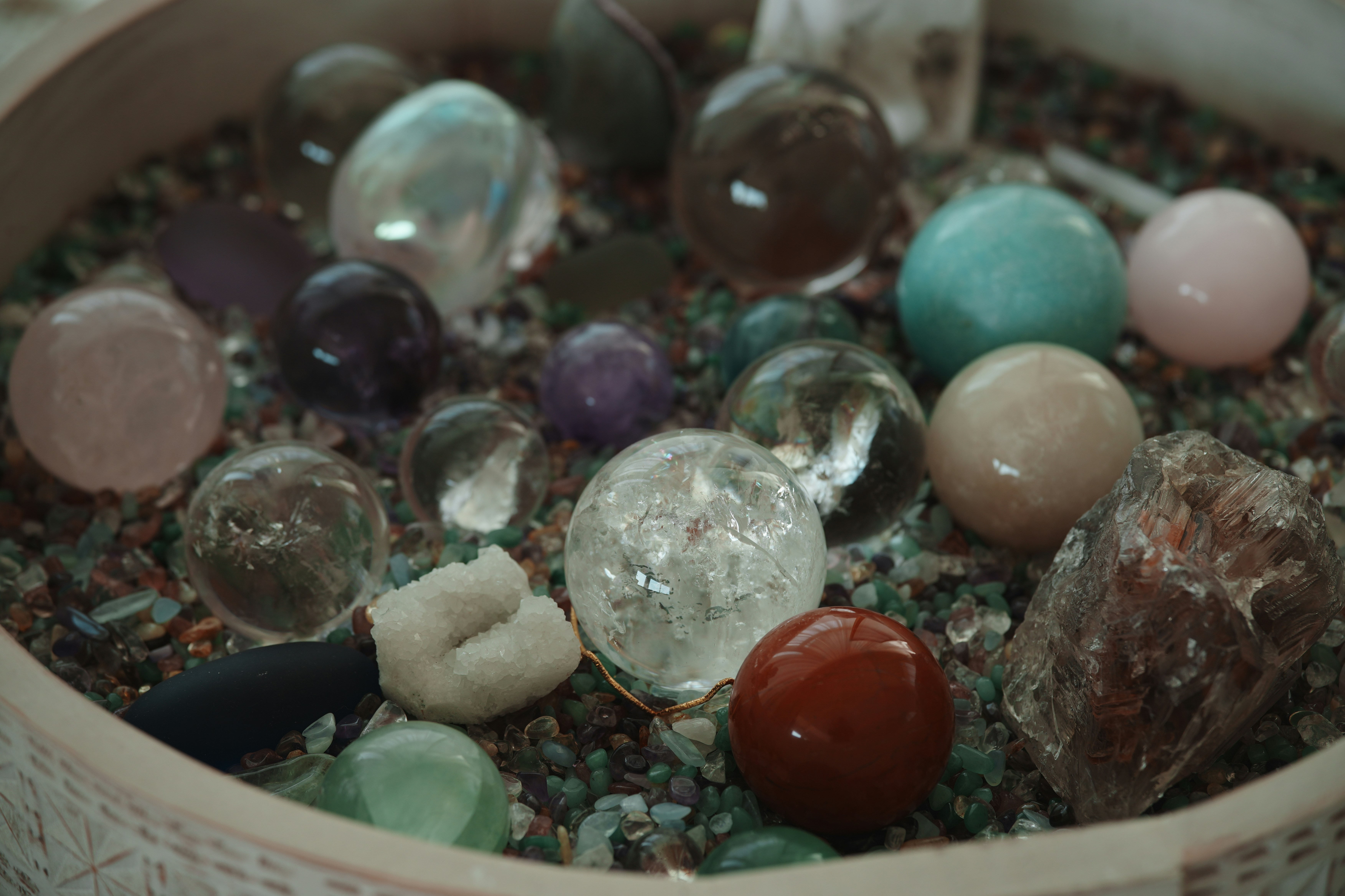 Various colorful crystal spheres and rough stones in gravel.