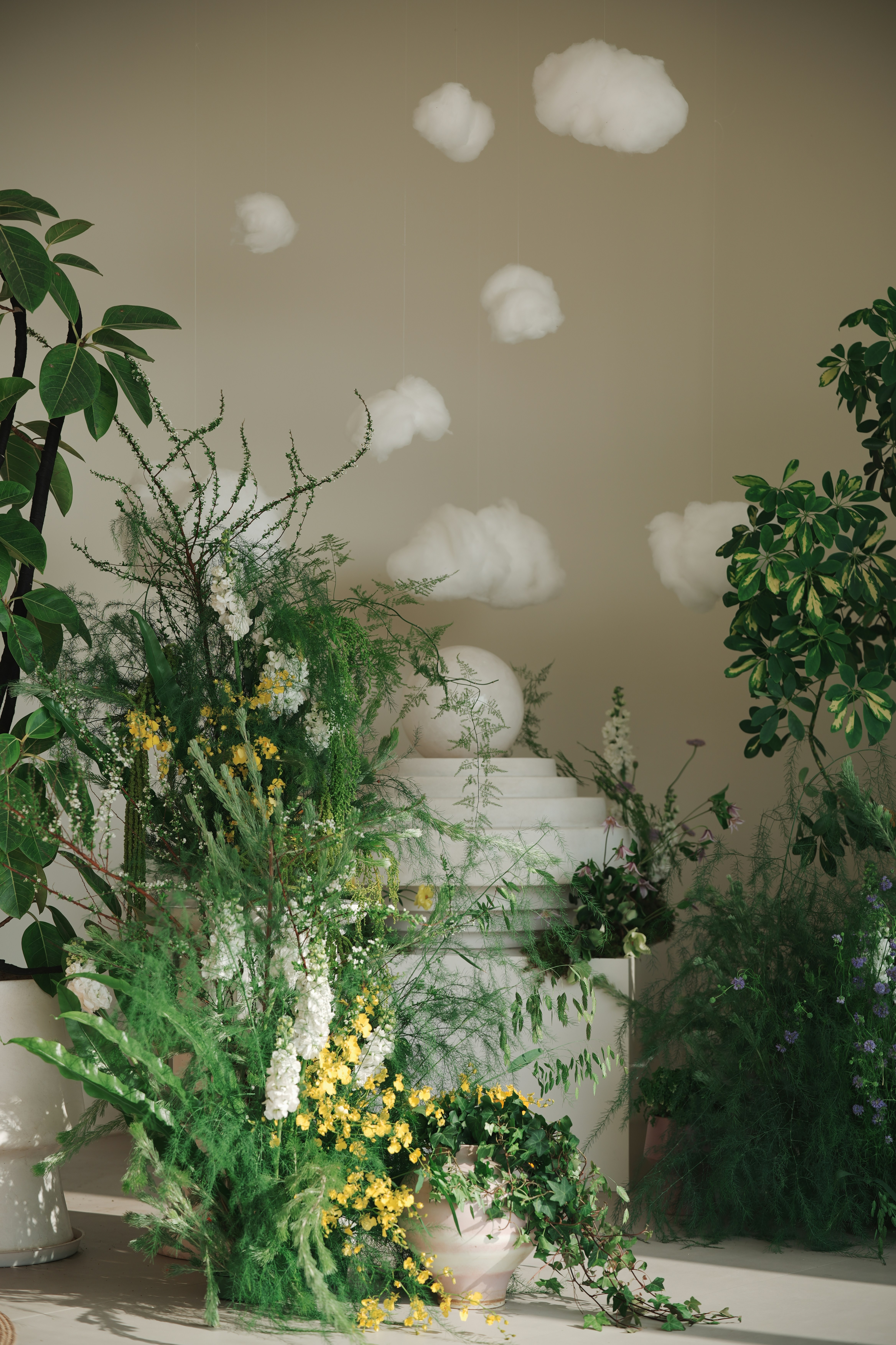 Lush greenery and white flowers with decorative clouds above.