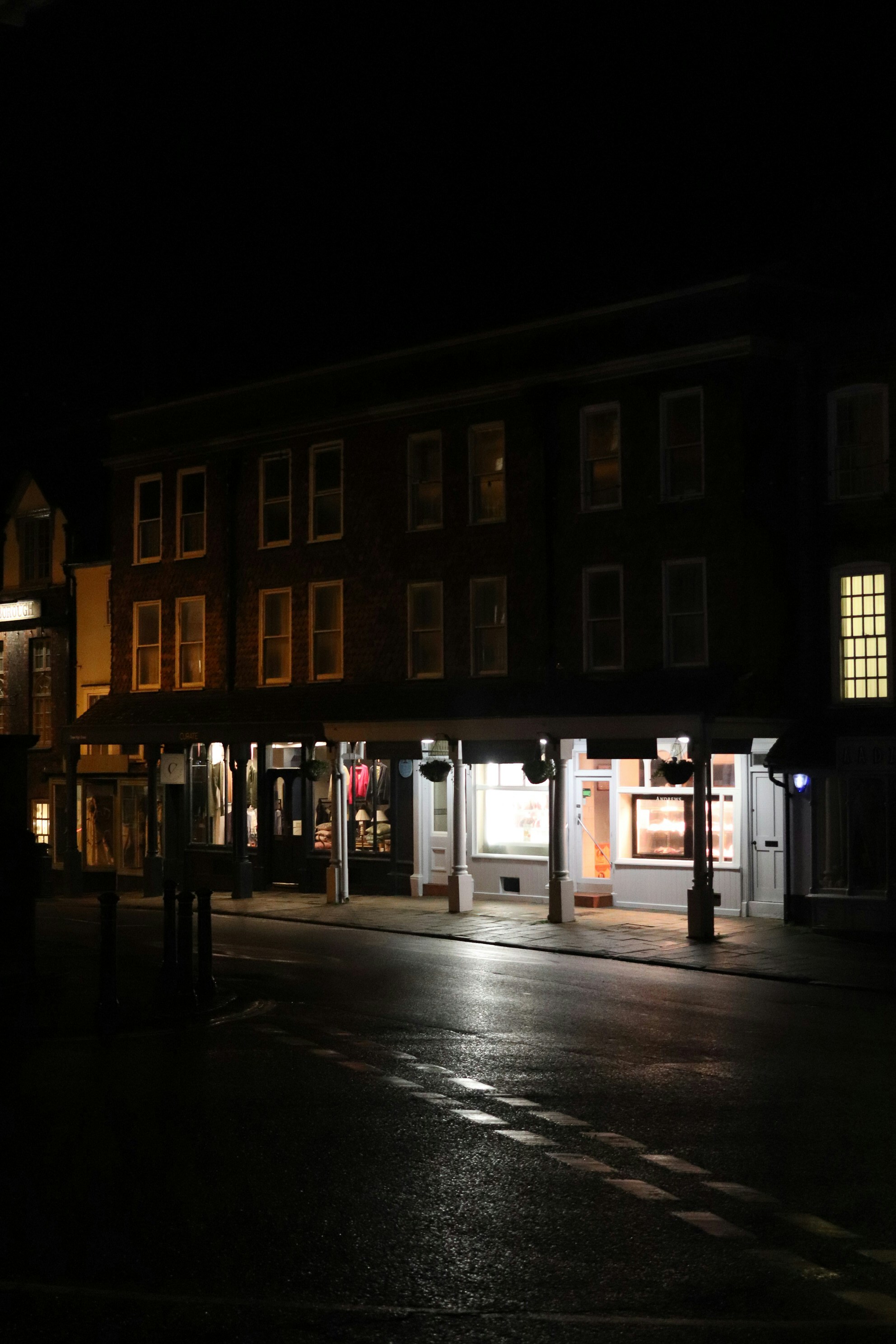 Straße mit nächtlichen Geschäften und nassem Gehweg