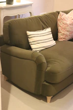 A comfortable green sofa with decorative pillows