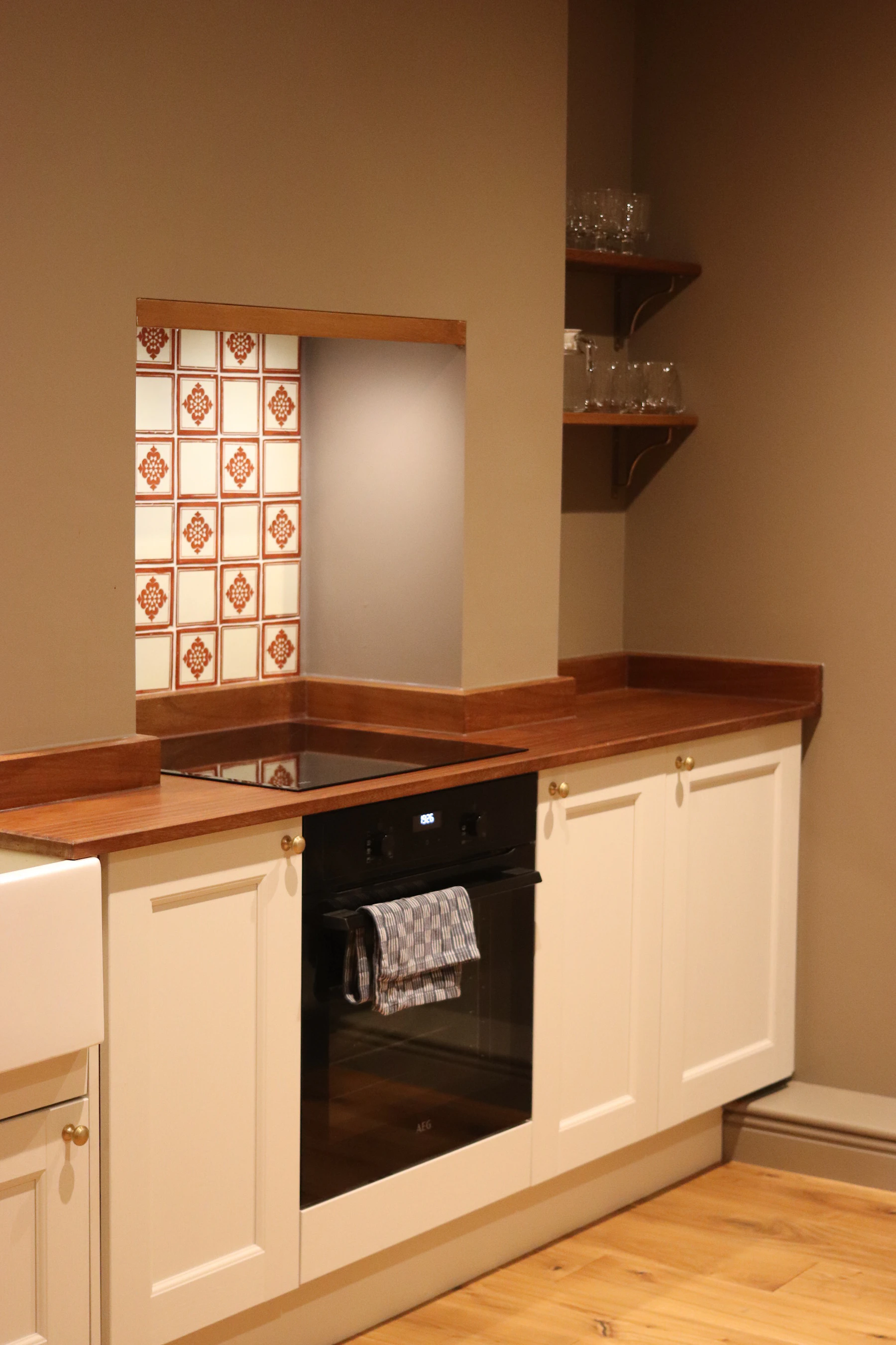 Painted kitchen cabinet run with warm counters and tile backsplash