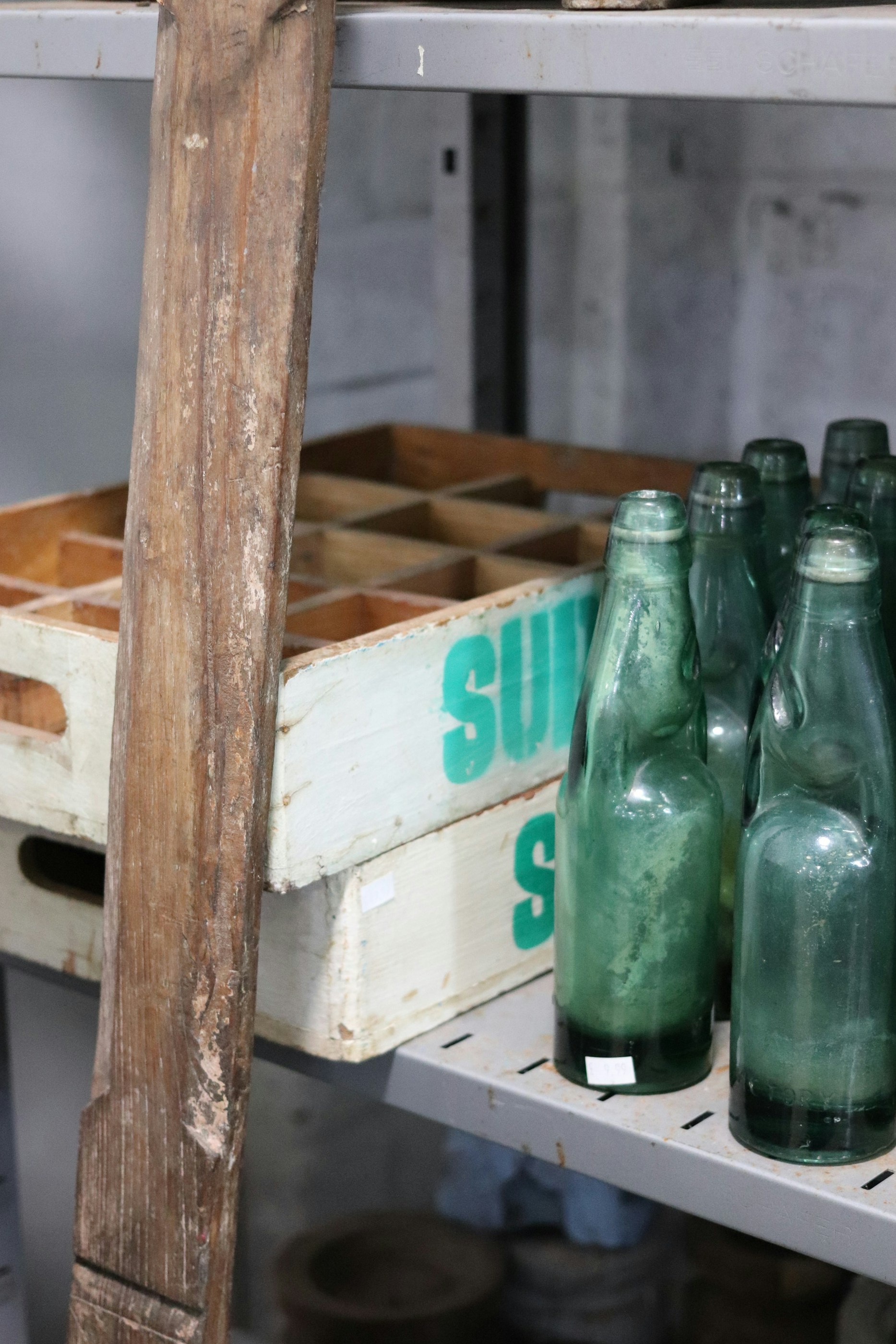 Des bouteilles en verre vert sur une étagère avec des caisses