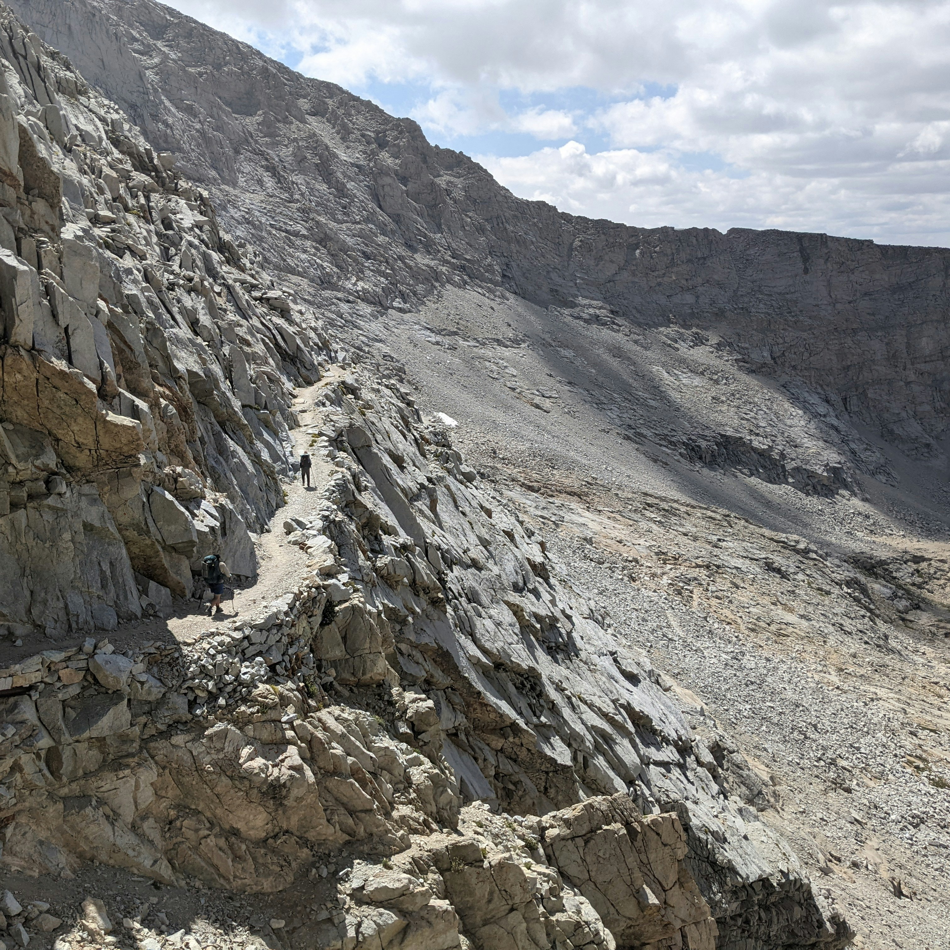 A narrow mountain trail winds along a rocky slope.