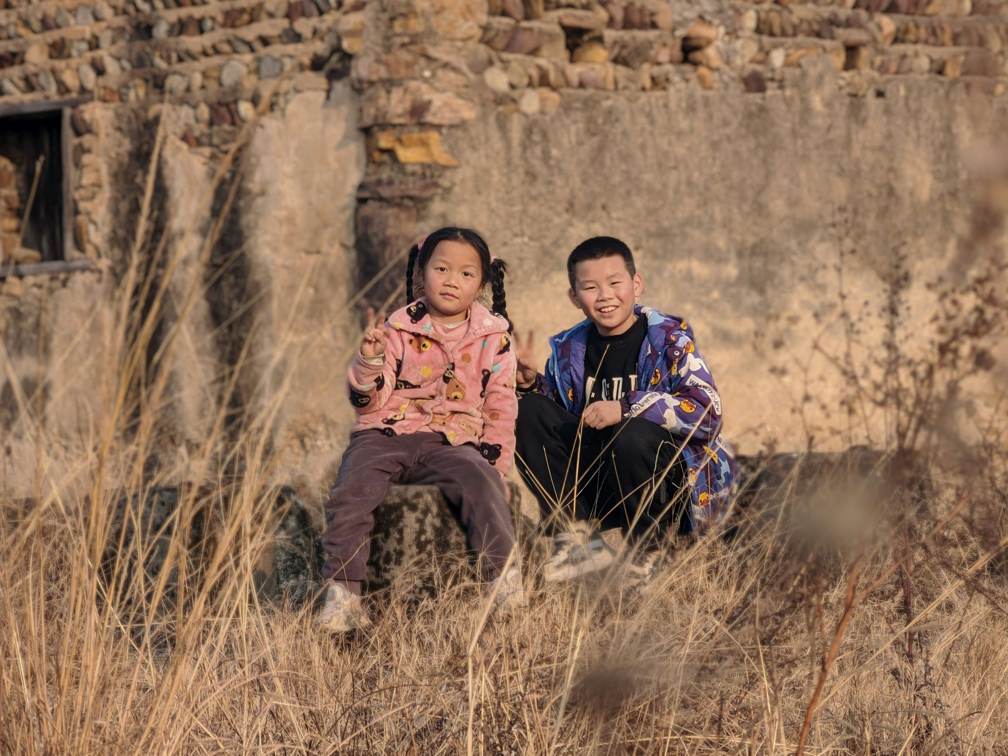 Two children sitting in front of an old building.