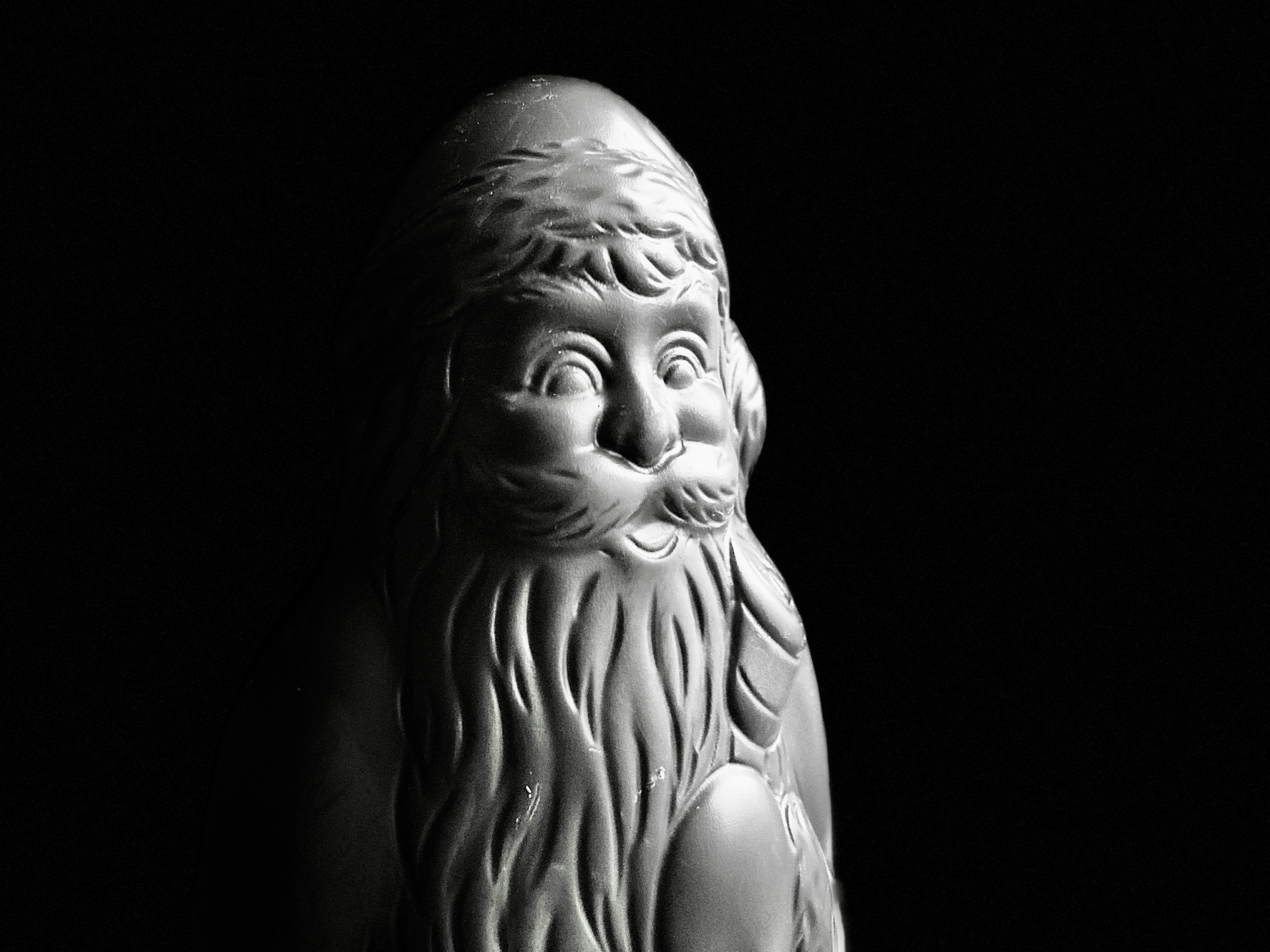 黒い背景に白いサンタクロースの像があった