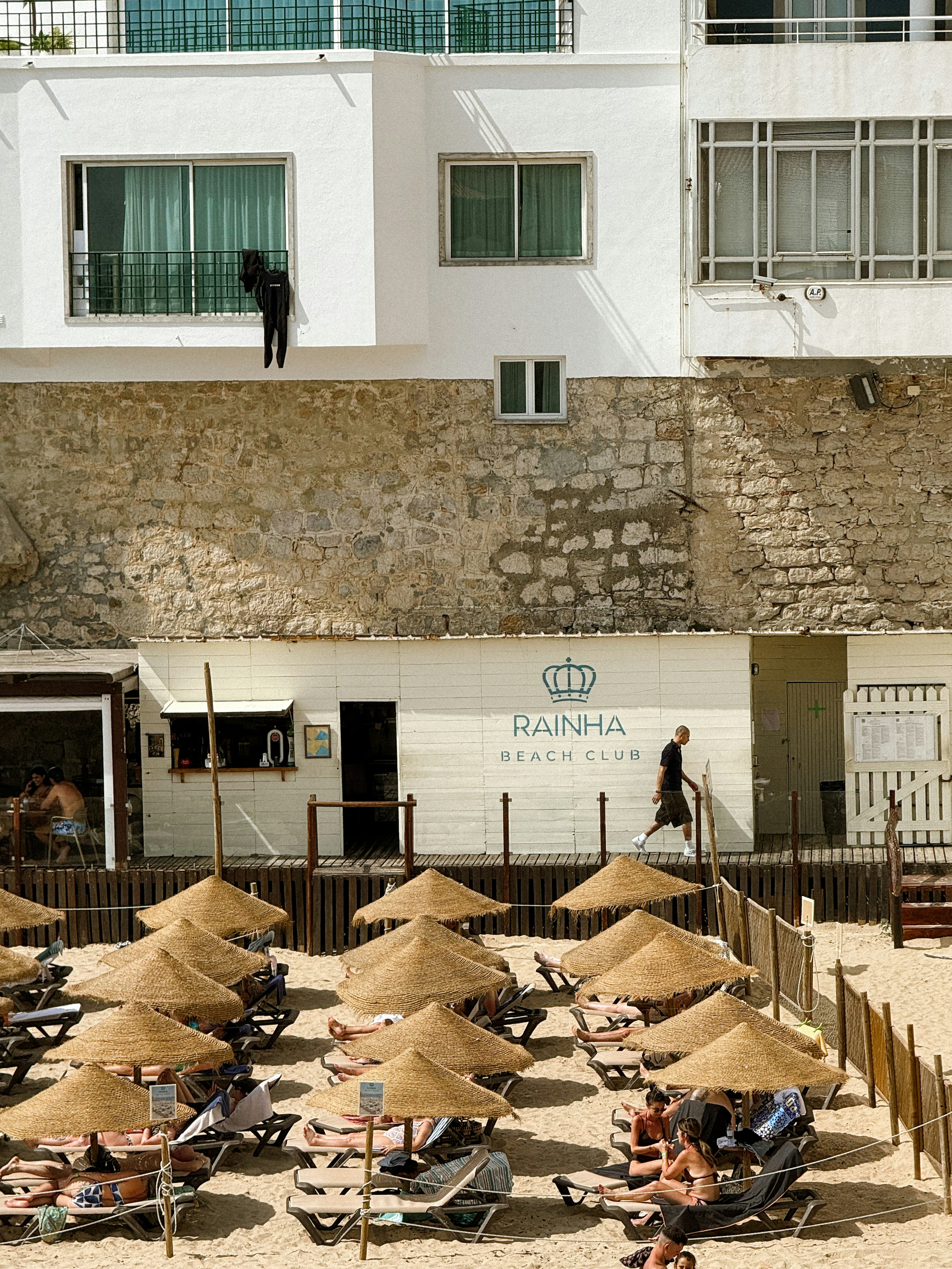 Beach chairs and umbrellas on sandy beach near building.