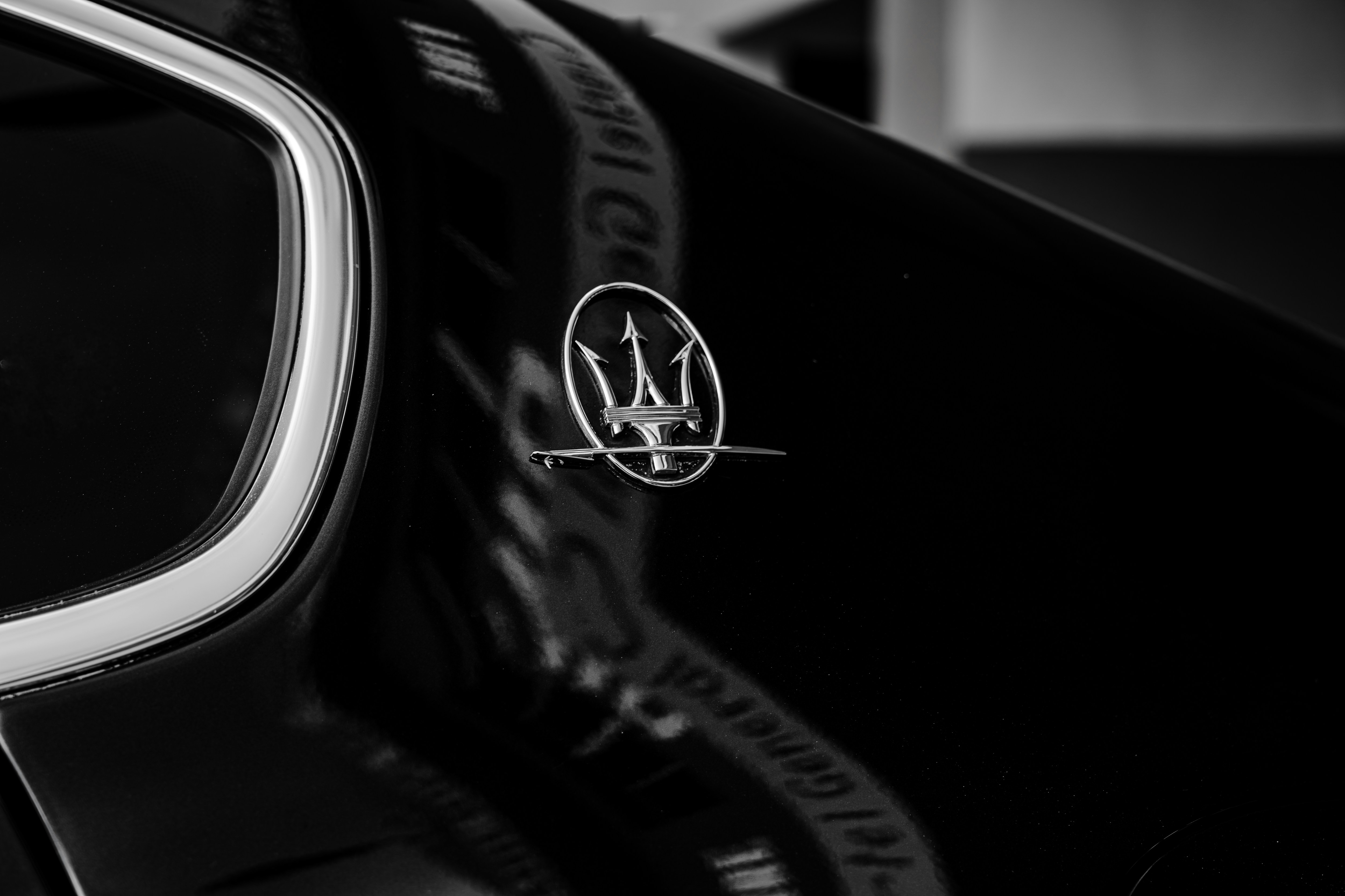 Close-up of a black car's maserati emblem.