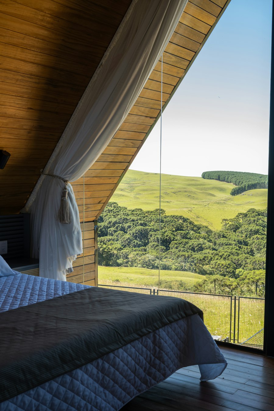 Chambre claire dont la grande baie ouvre sur des collines verdoyantes