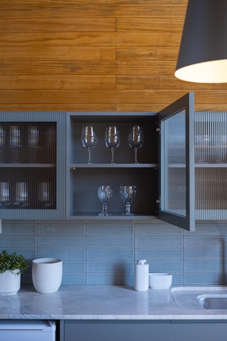 Kitchen cabinets with glassware and wooden wall paneling.