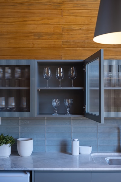 Kitchen cabinets with glassware and wooden wall paneling.